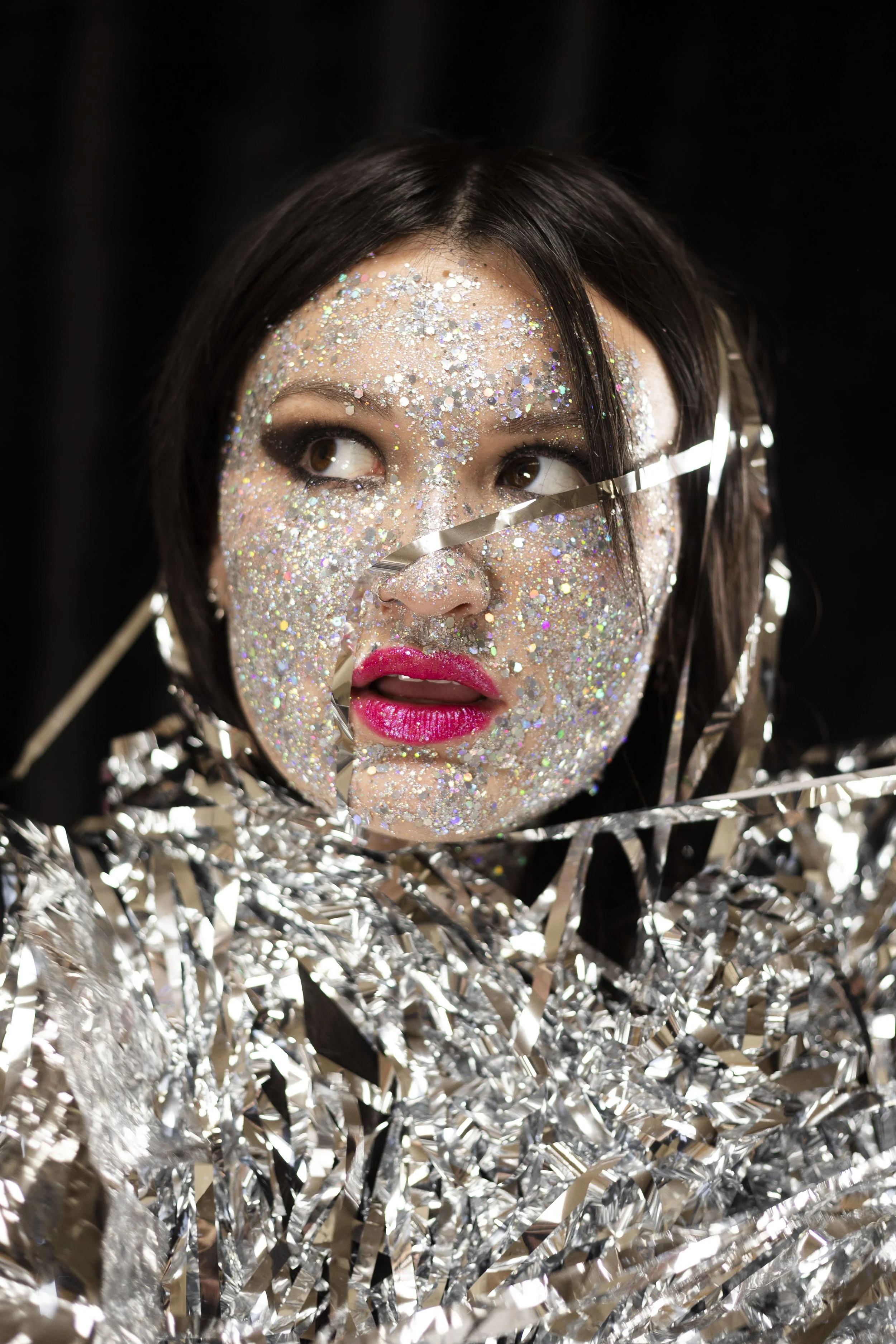  Close photo of models head and shoulder with party tinsel. Model face covered in glitter 