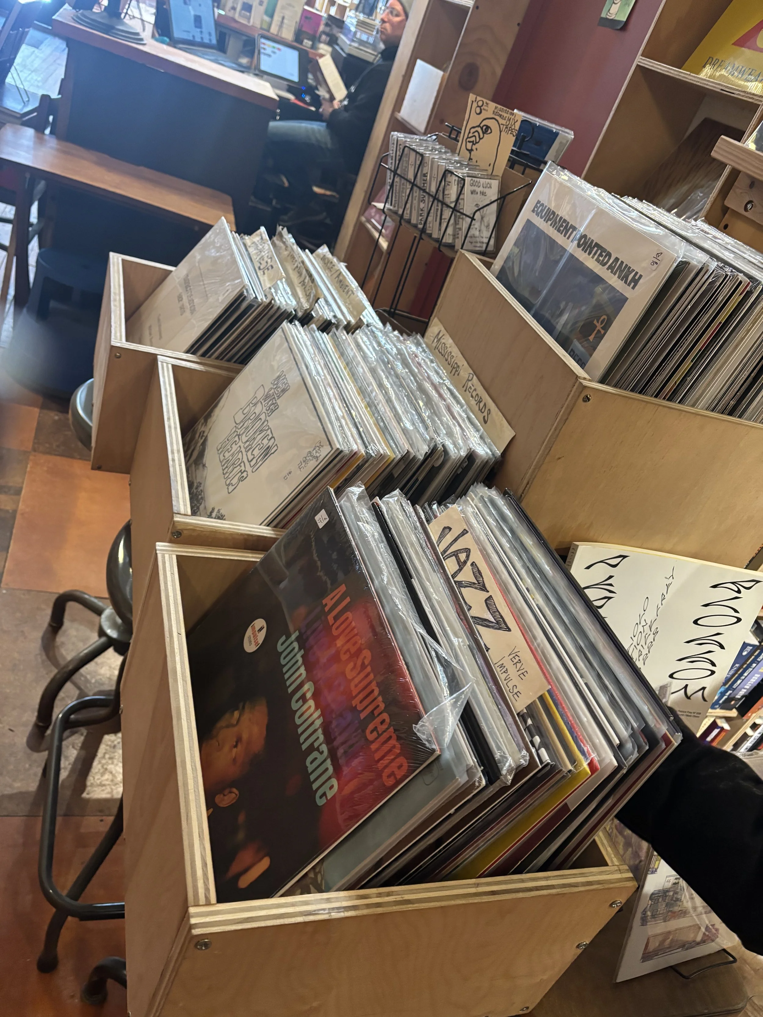 bat Books interior with wall-to-wall shelves and a small table of stacked books 
