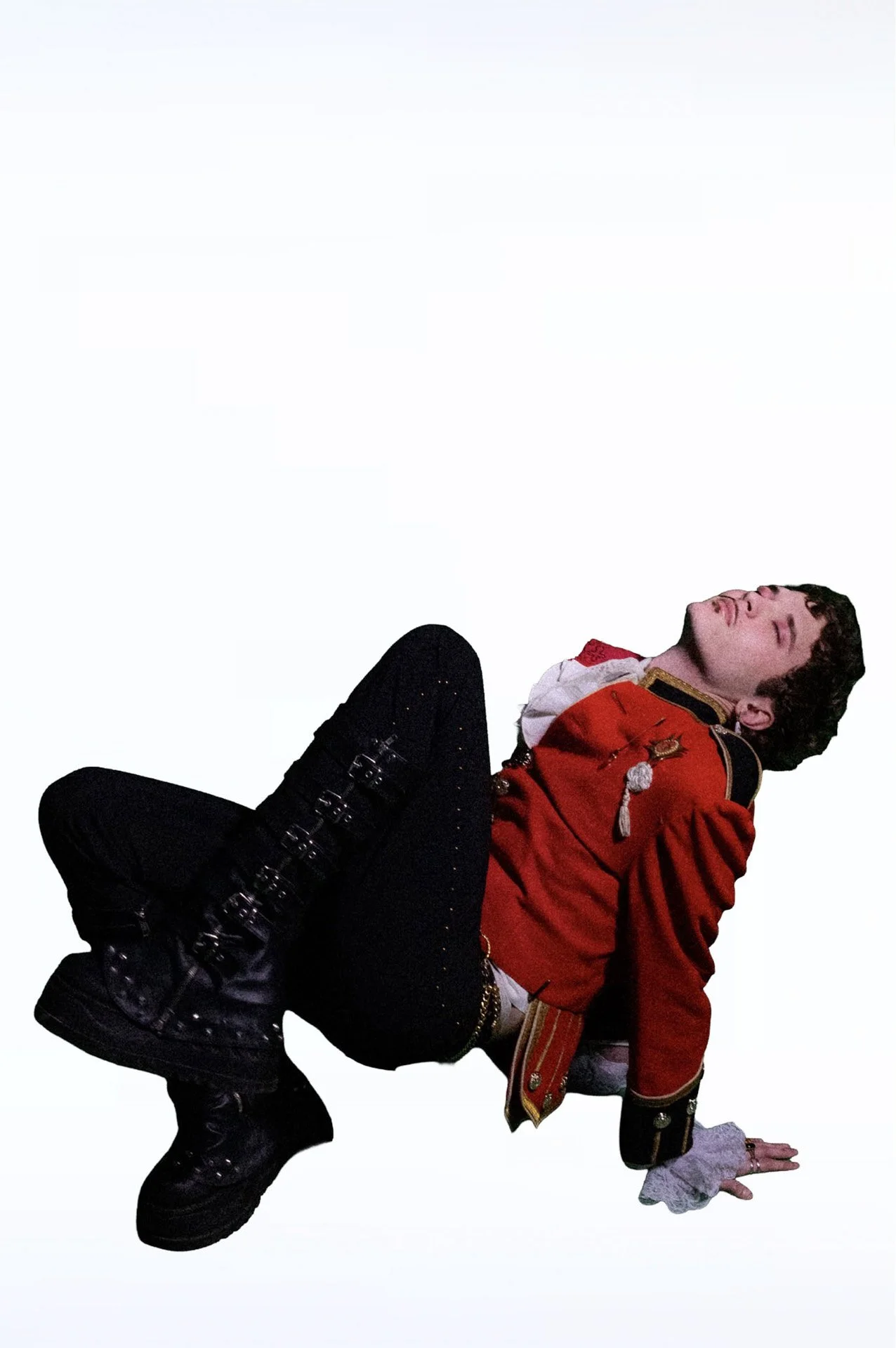  Person in a red military-style jacket and black boots standing against a white background. 