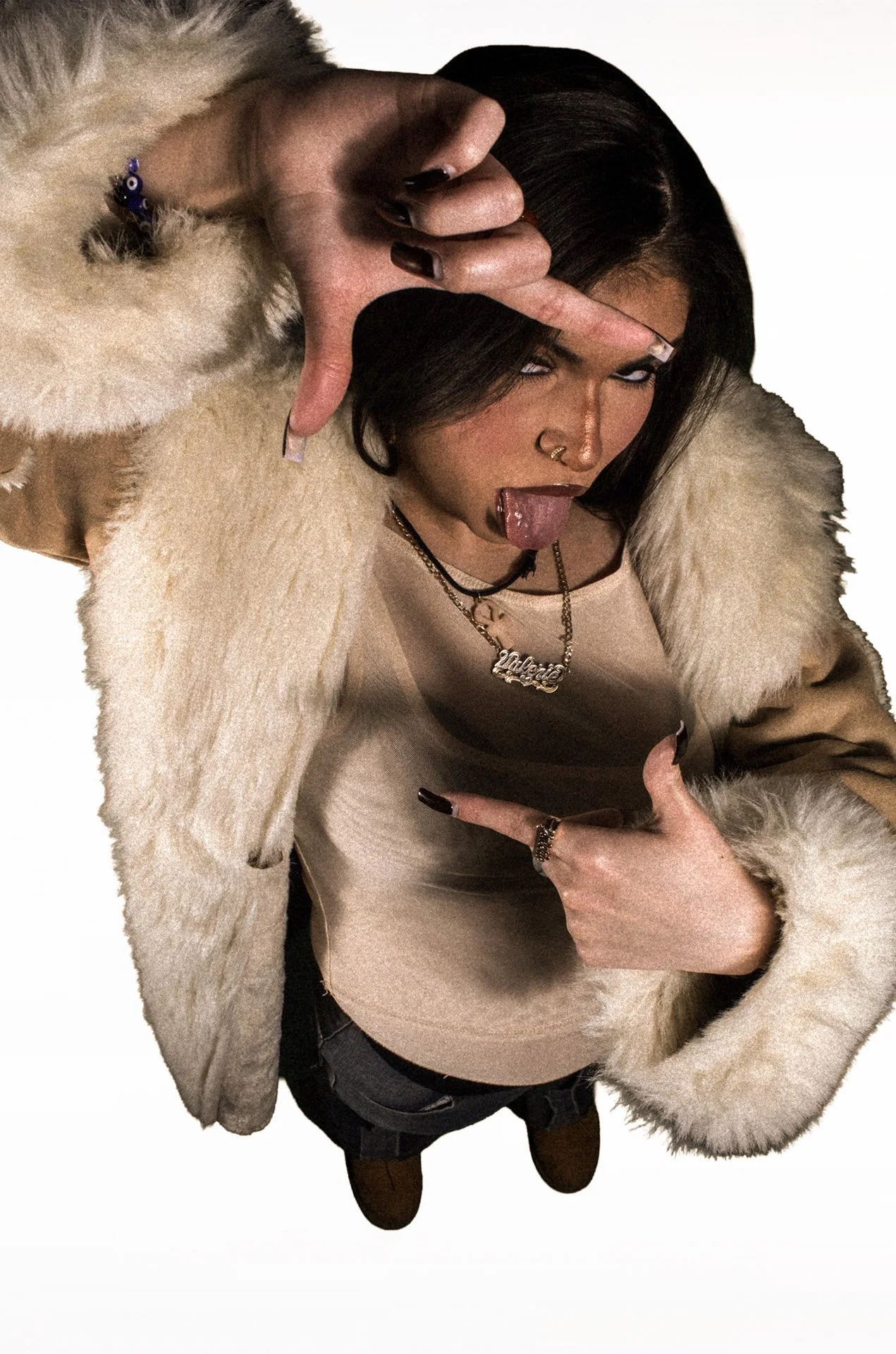  Person in a sheer top holding a fluffy jacket looking down at it against a plain background. 