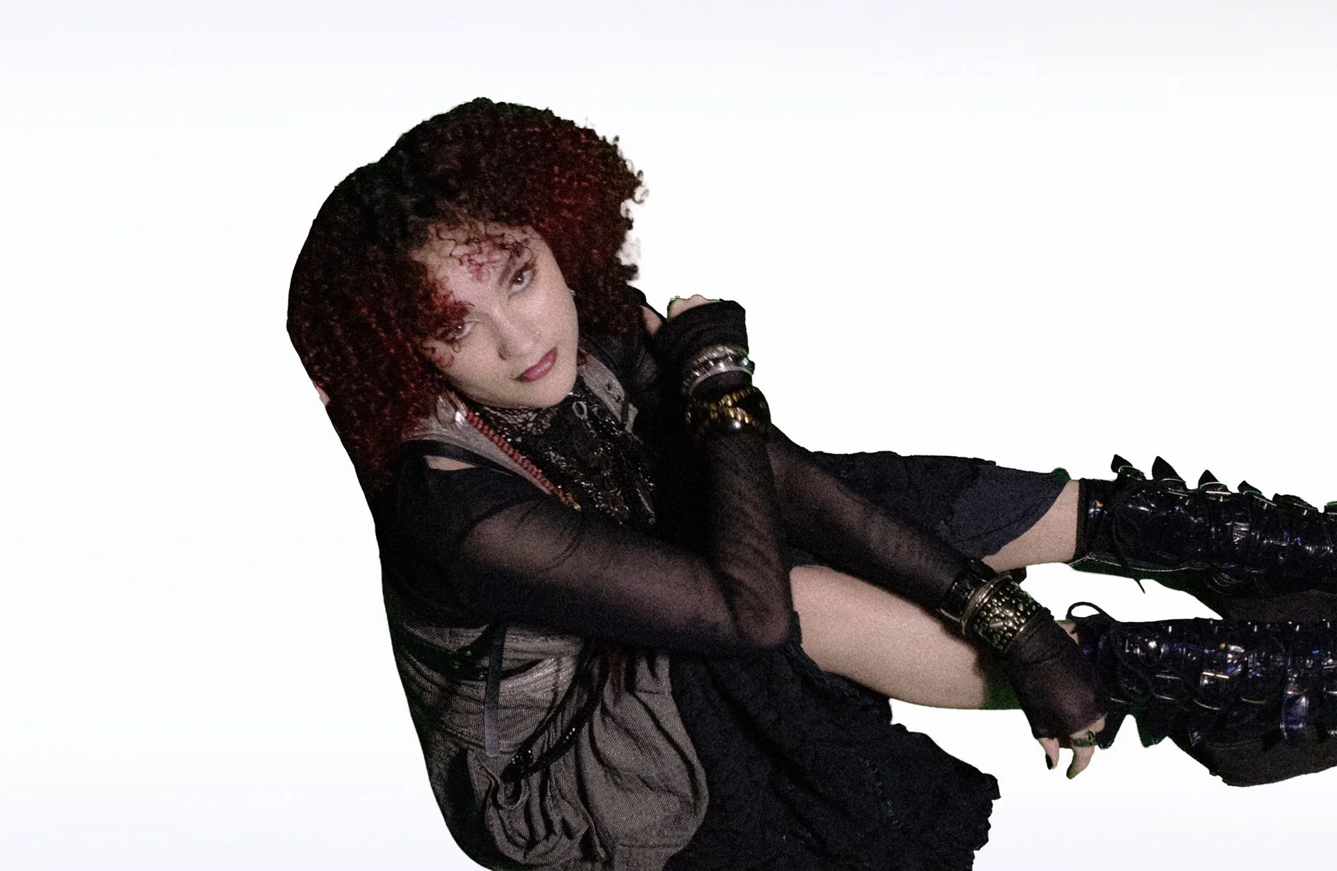  Close-up of person with curly red hair in layered necklaces. 