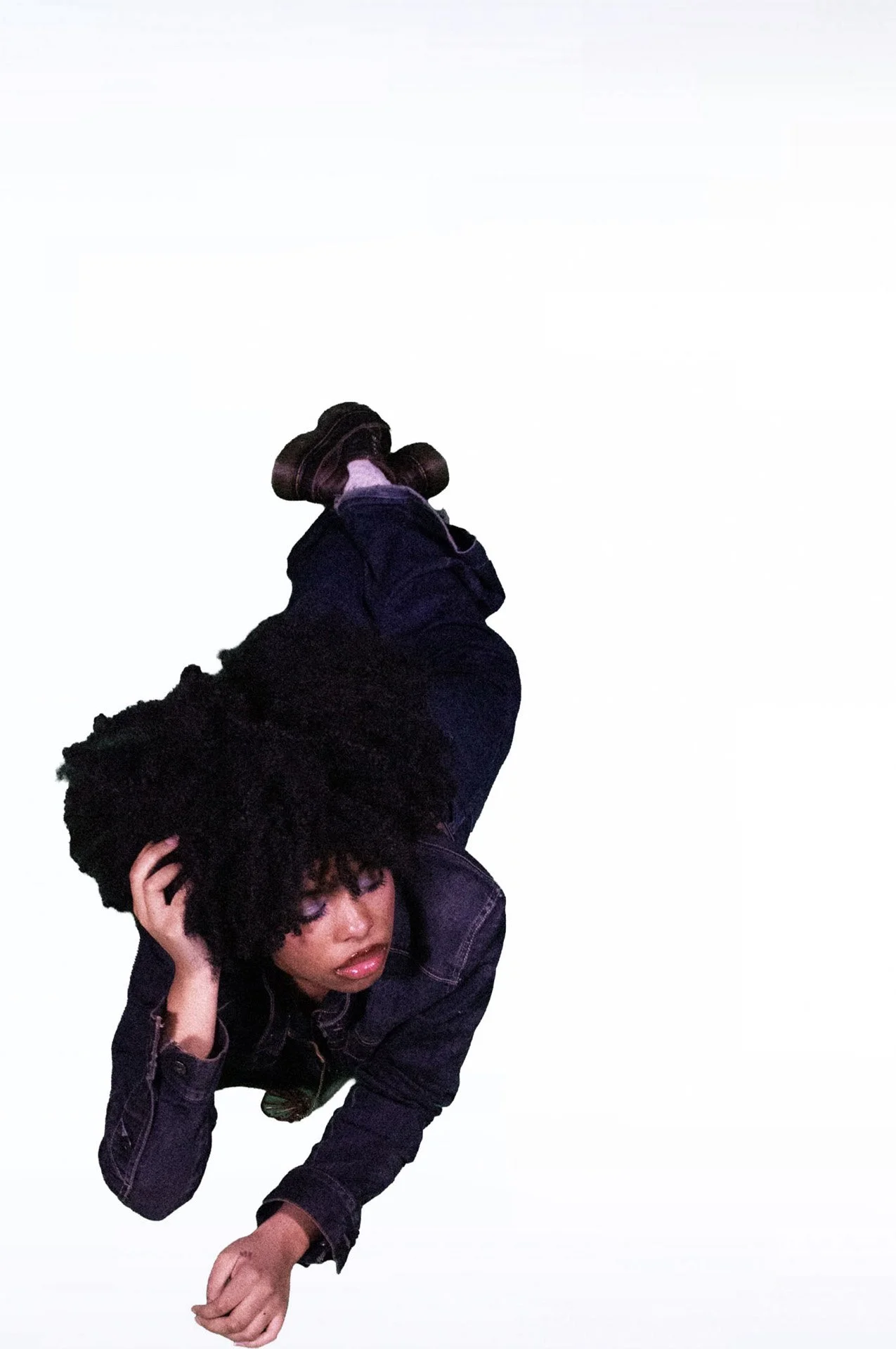  Person lying sideways with voluminous curls and denim.   