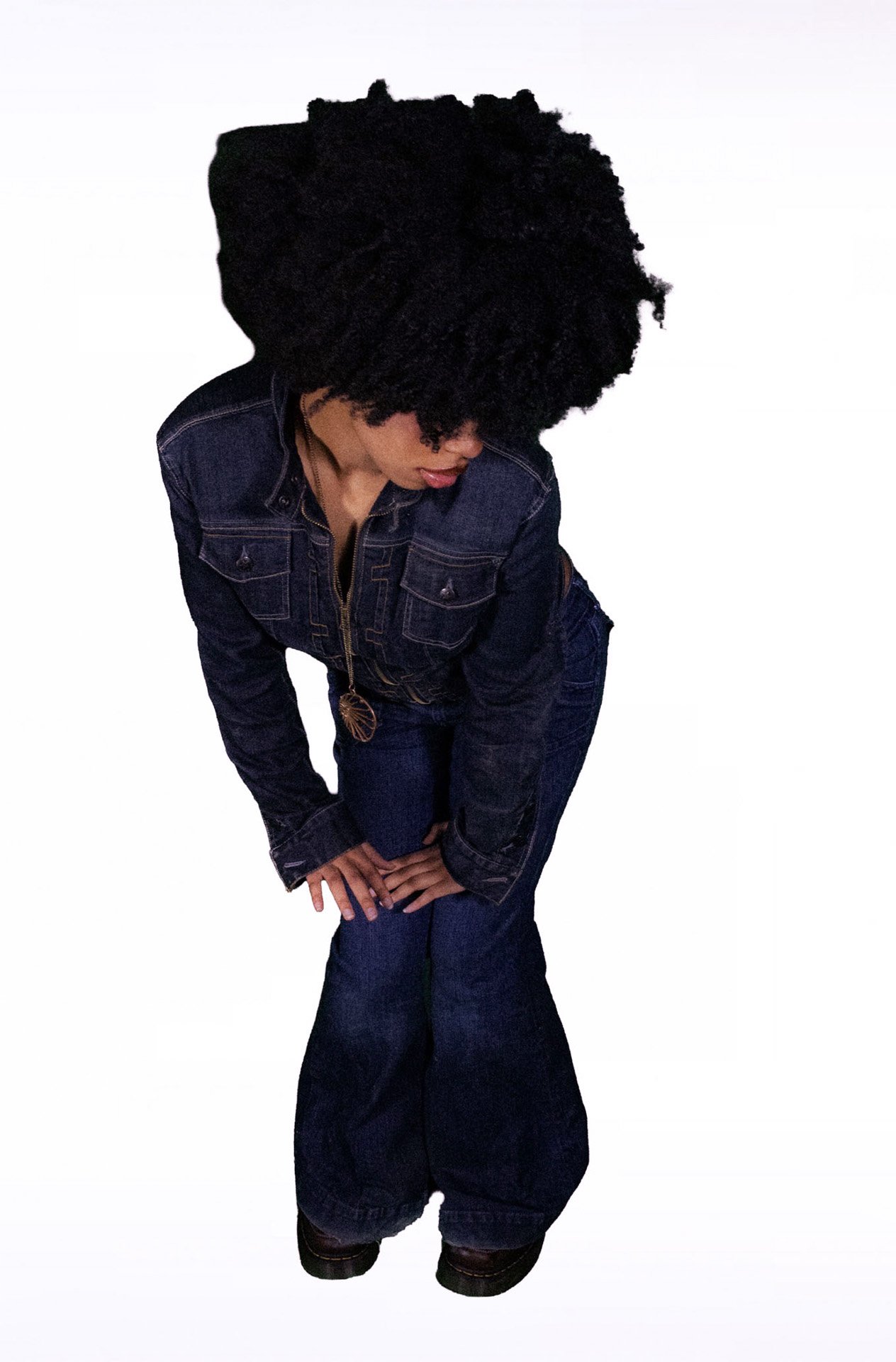  Person bending forward wearing a denim jumpsuit.   