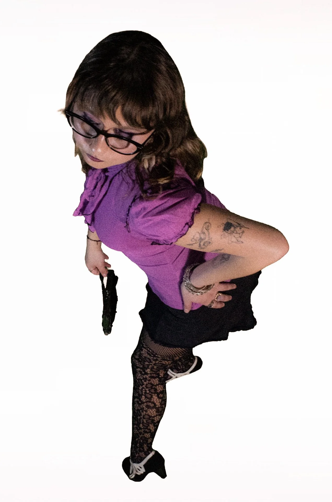  Person posing in a purple blouse, skirt, and lace tights. 