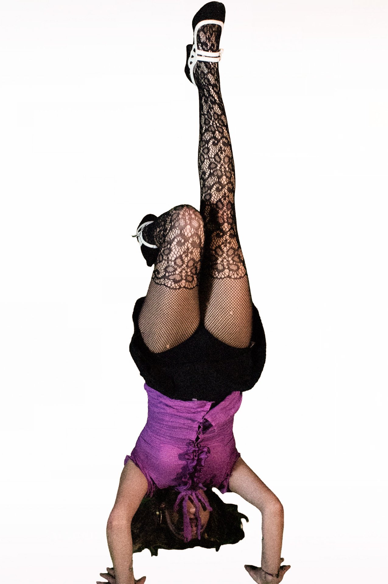  Person doing a headstand wearing lace tights and heels.   