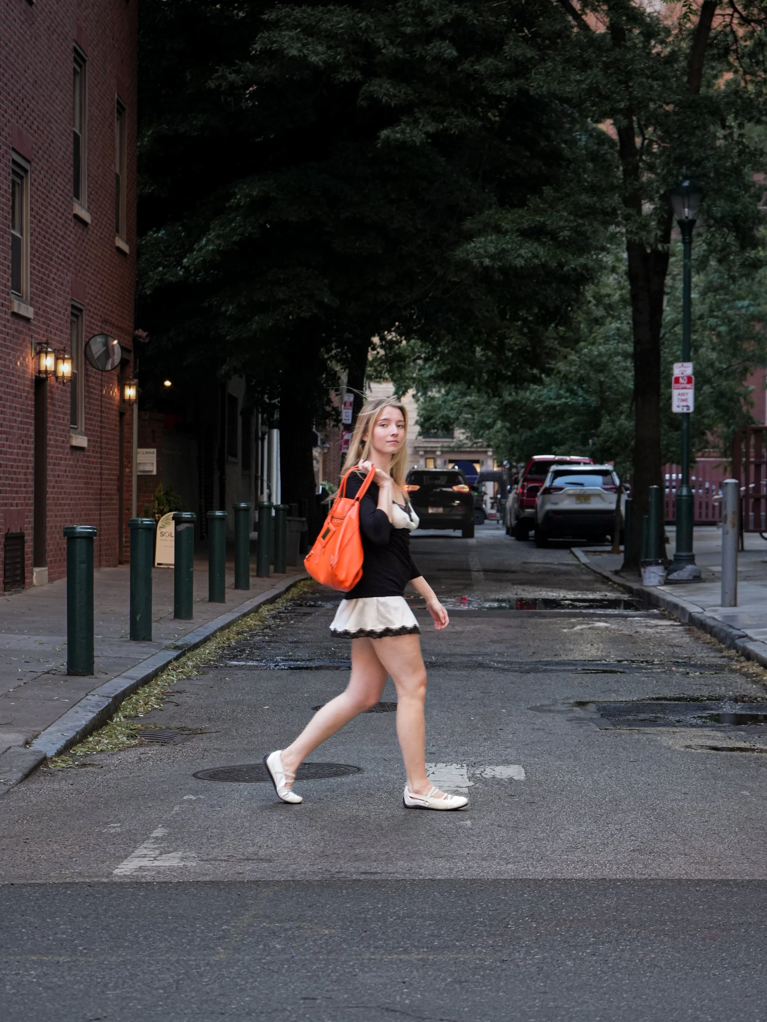 A woman poses alone with an orange Balenciaga bag in a fashion editorial image about self-worth and consumption.