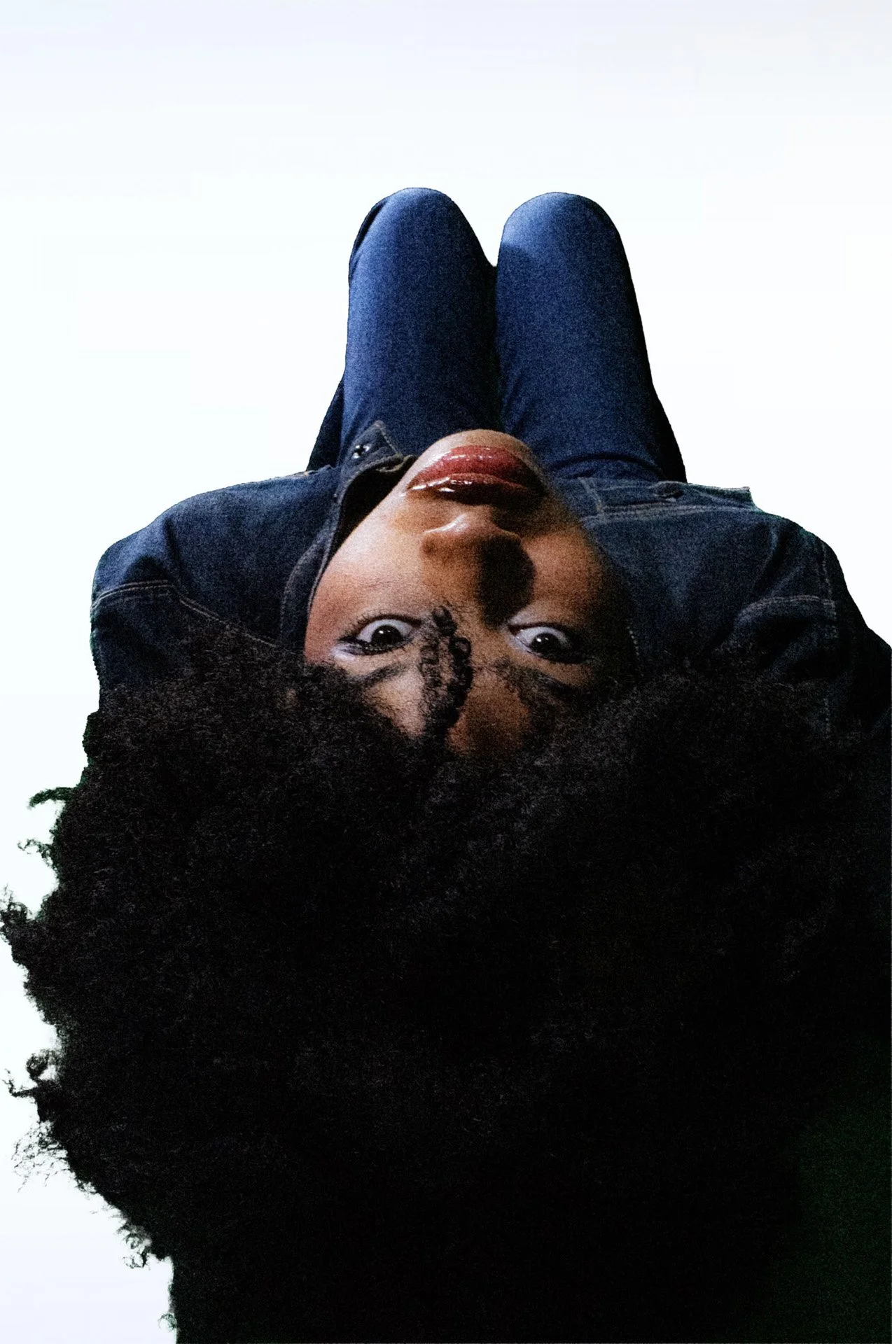 Person upside down with large natural curls and denim outfit.