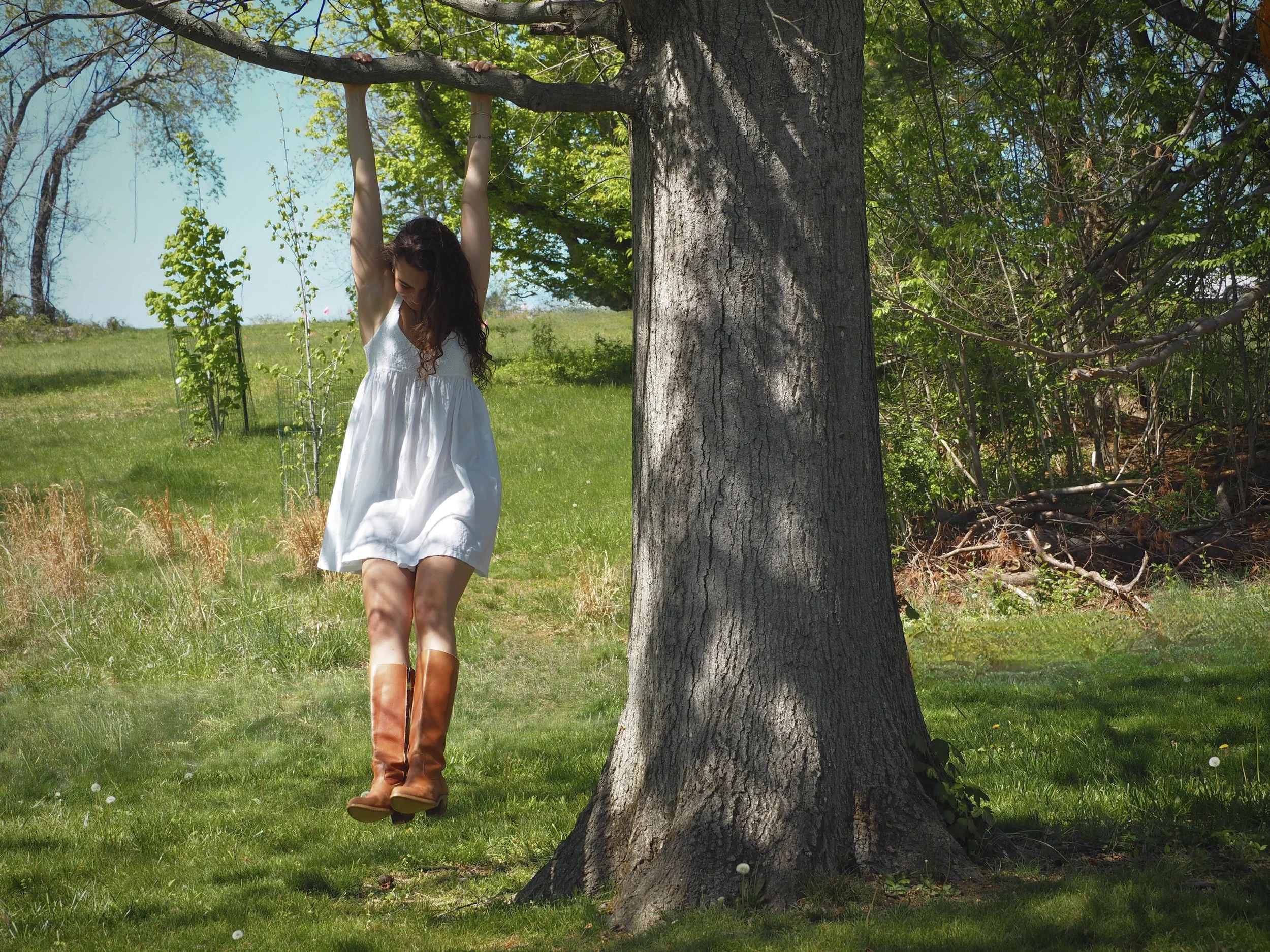 girl in white dress swinging from tree