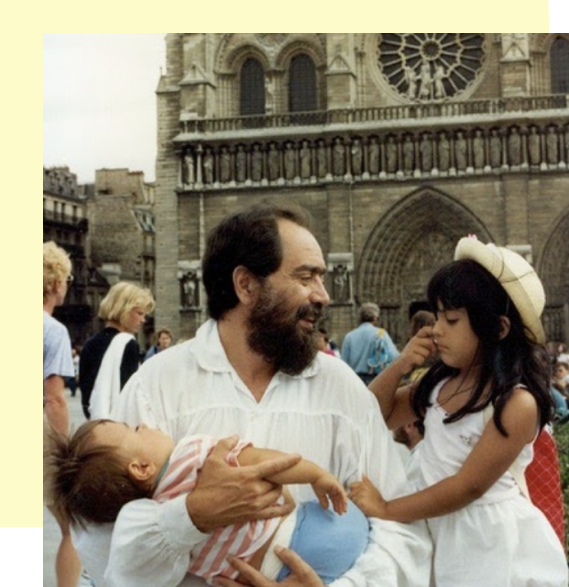 4 year old Melina Gac Levin and her 1 year old brother with their father in front of Notre Dame in Paris 1989. Her brother is asleep in her father's arms. Melina is holding her father's arm and he is smiling at her.