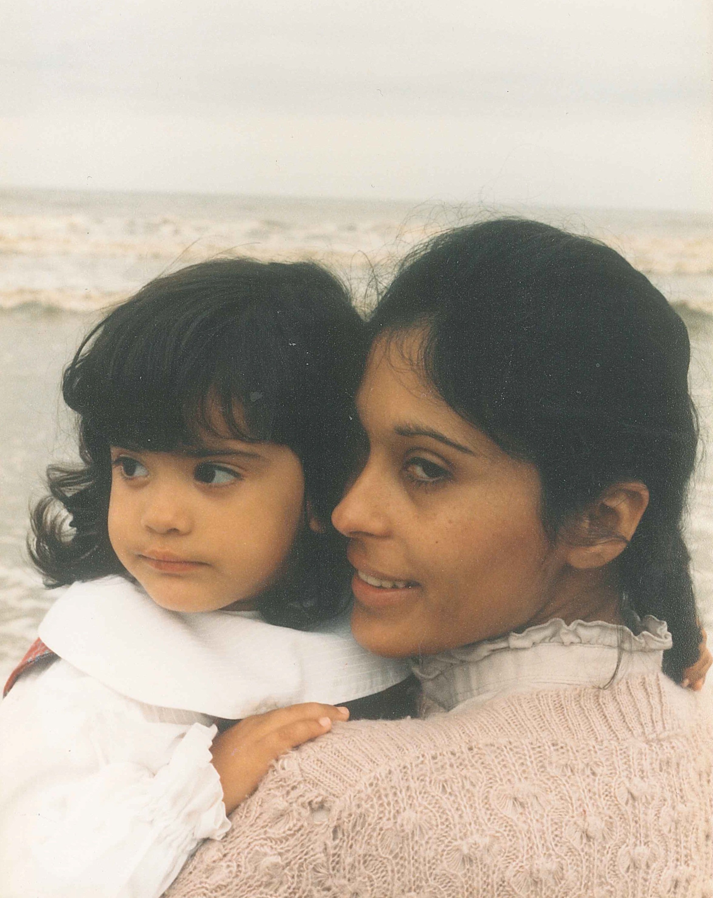 Two year old Melina Gac Levin carried by her Puerto Rican mother on the beach in Holland during winter..