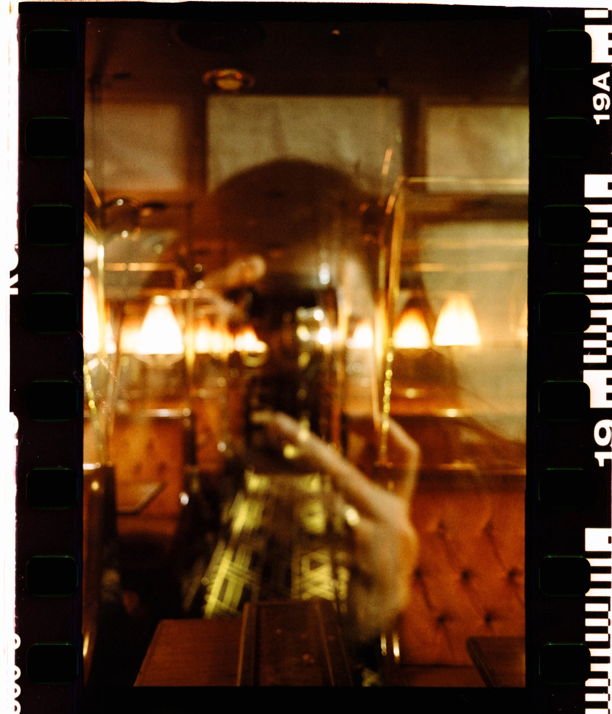 Reflet flou d'une personne dans une vitre, avec éclairage tamisé et décoration en bois dans un intérieur de restaurant ou café.