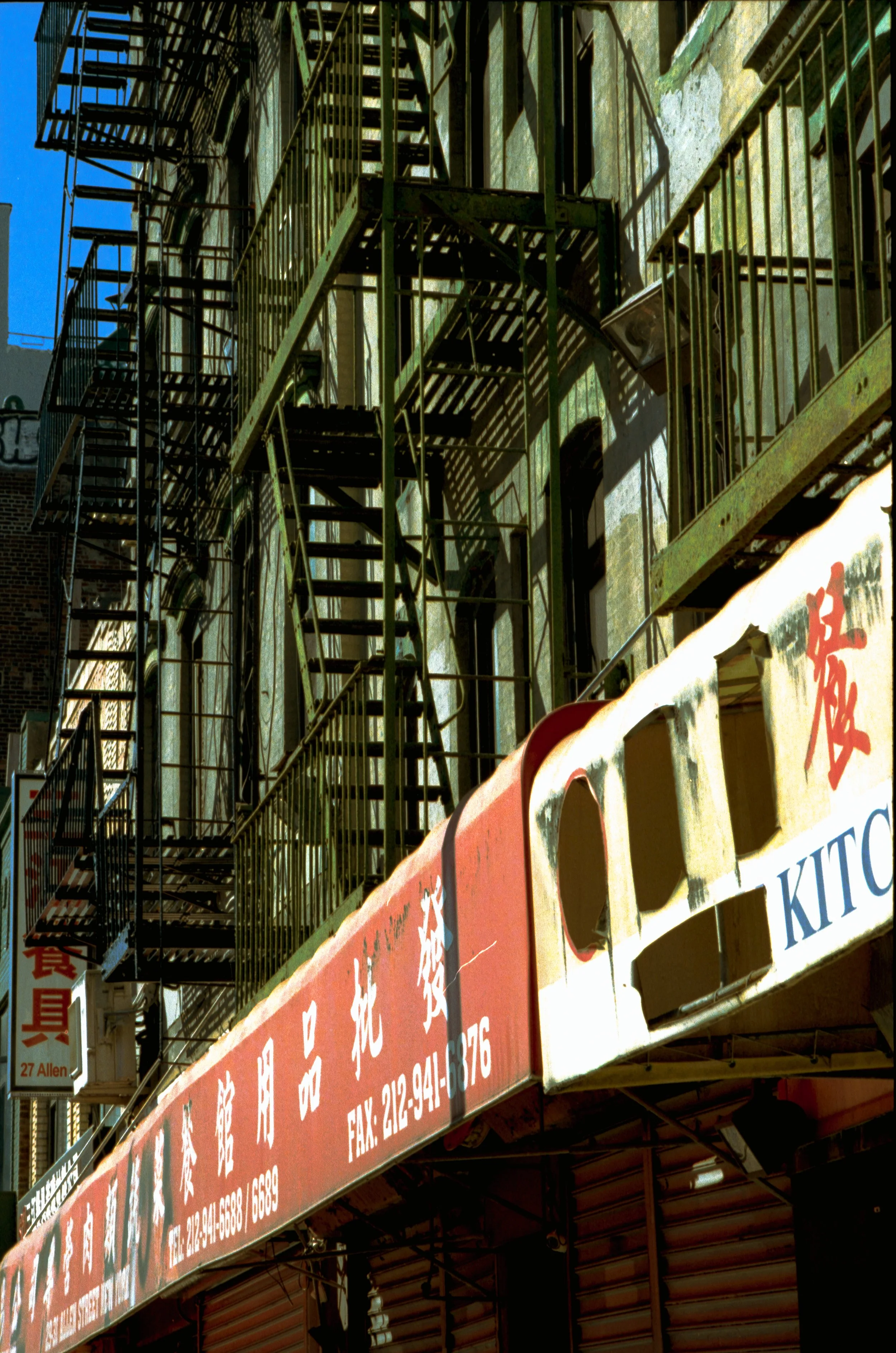 Structures en métal d'une façade en ville avec des escaliers extérieurs et des panneaux écrits en chinois.