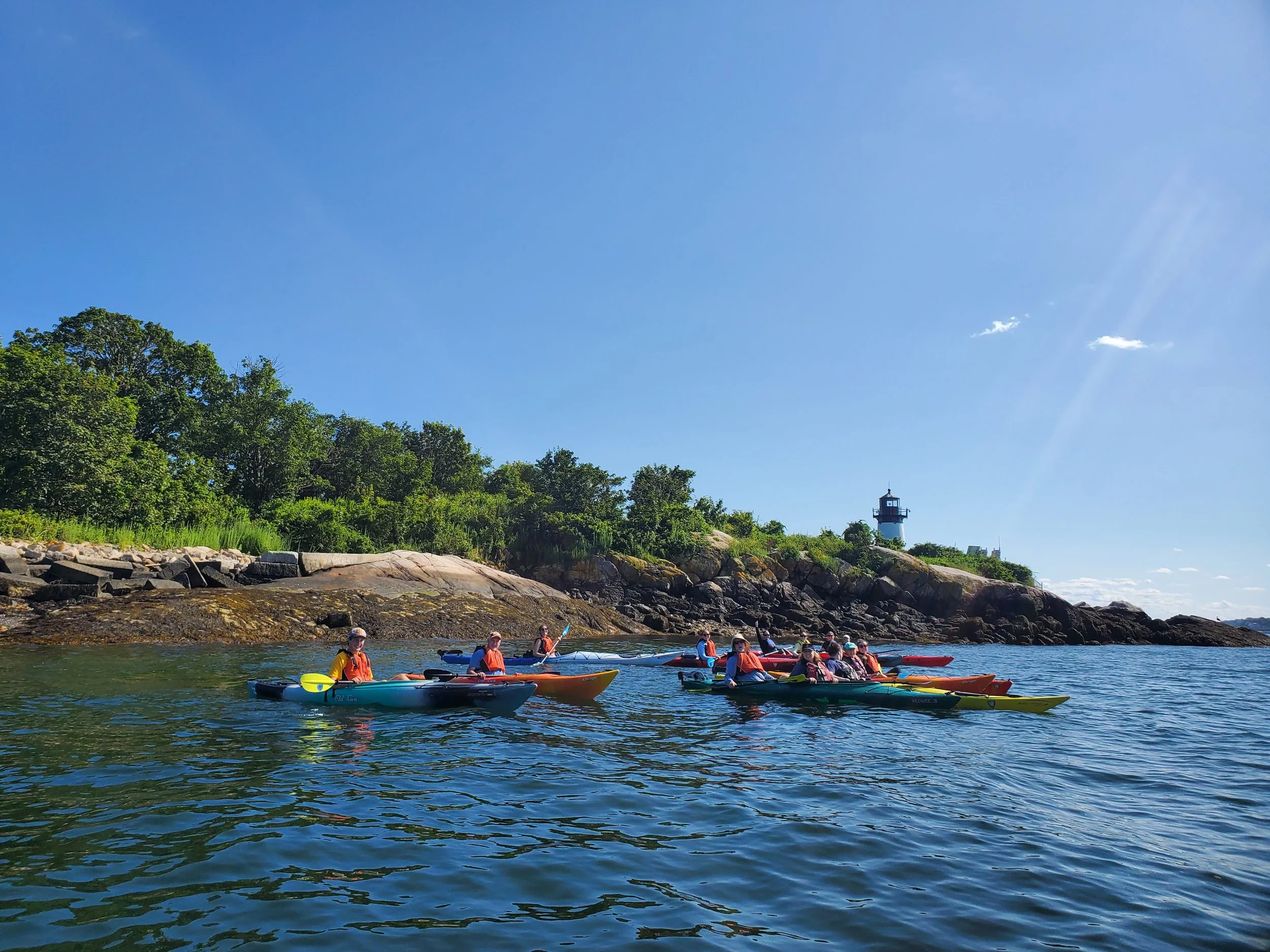 Moonlit beach scene with clouds over a calm sea, distant shoreline, and small illuminated structure on water.