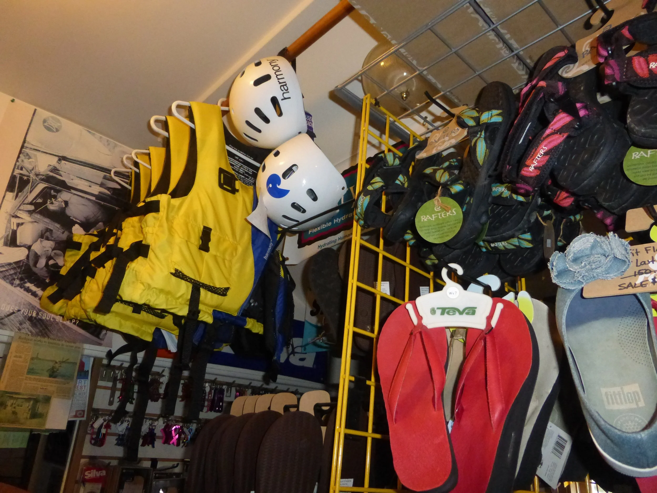 Outdoor sports equipment store display with helmets, life jackets, sandals, and flip-flops