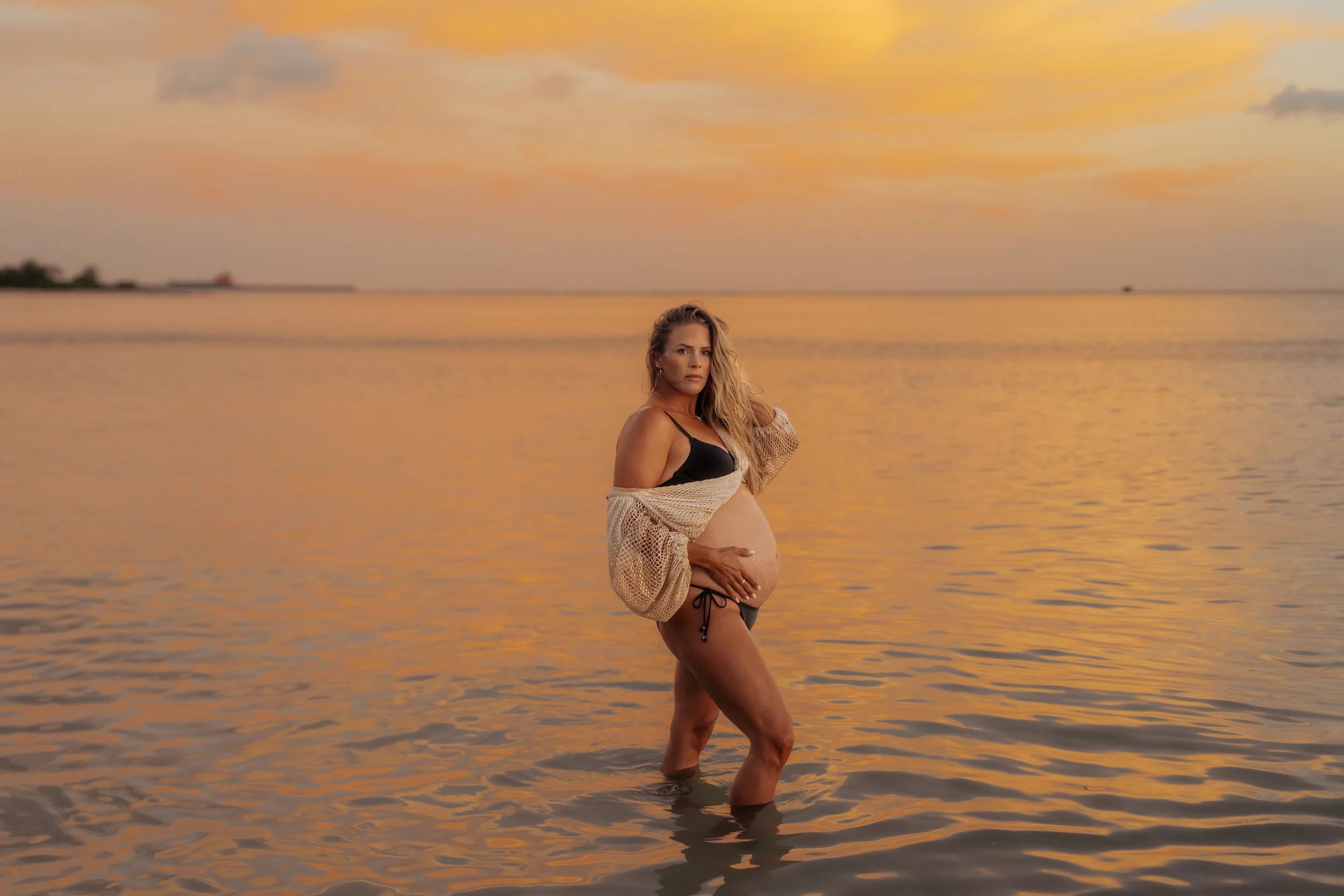Stunning golden sunset in calm O'ahu beach water with a gorgeous maternity mama 