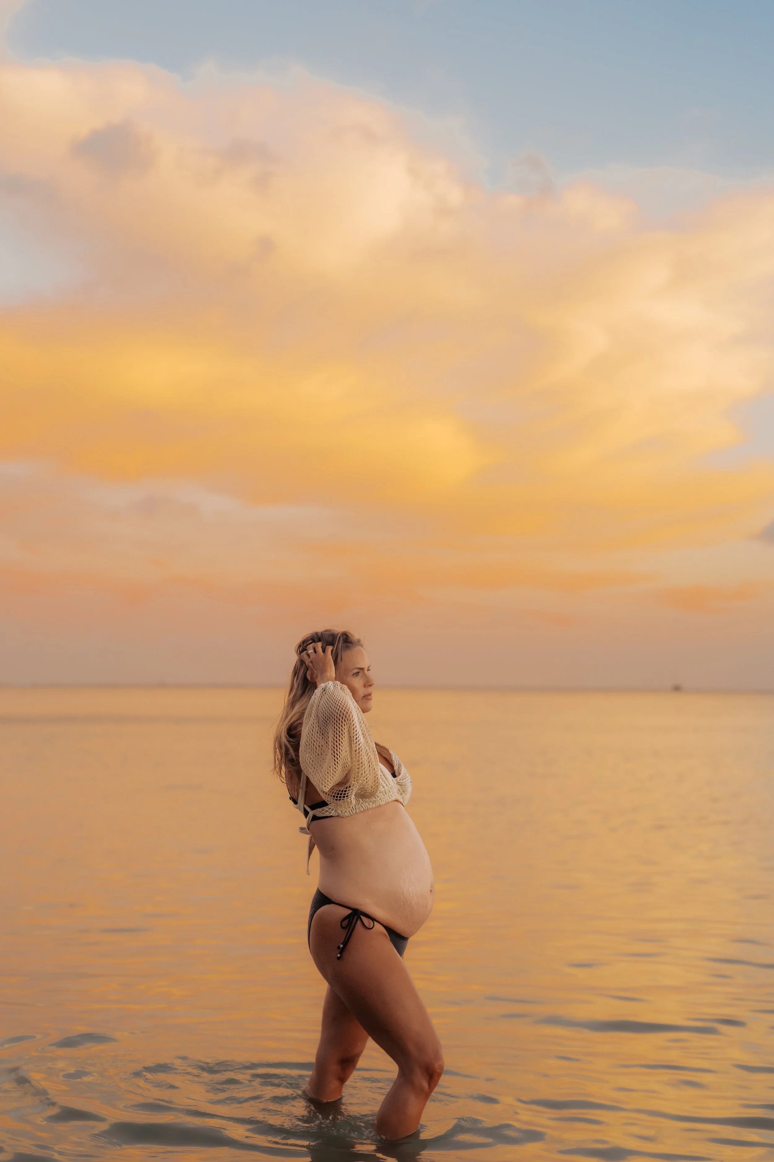 Stunning golden sunset in calm O'ahu beach water with a gorgeous maternity mama 