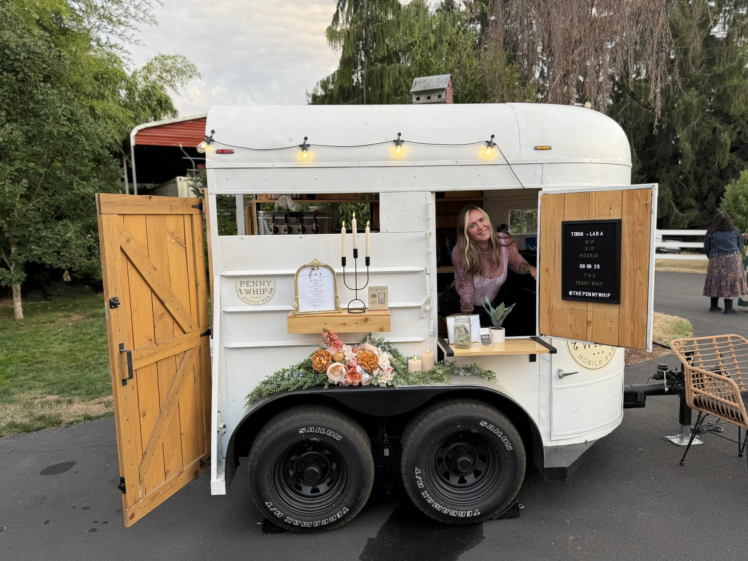 Owner Chelsie Kelly Posing in the trailer, with floral arrangements and beautiful decor!