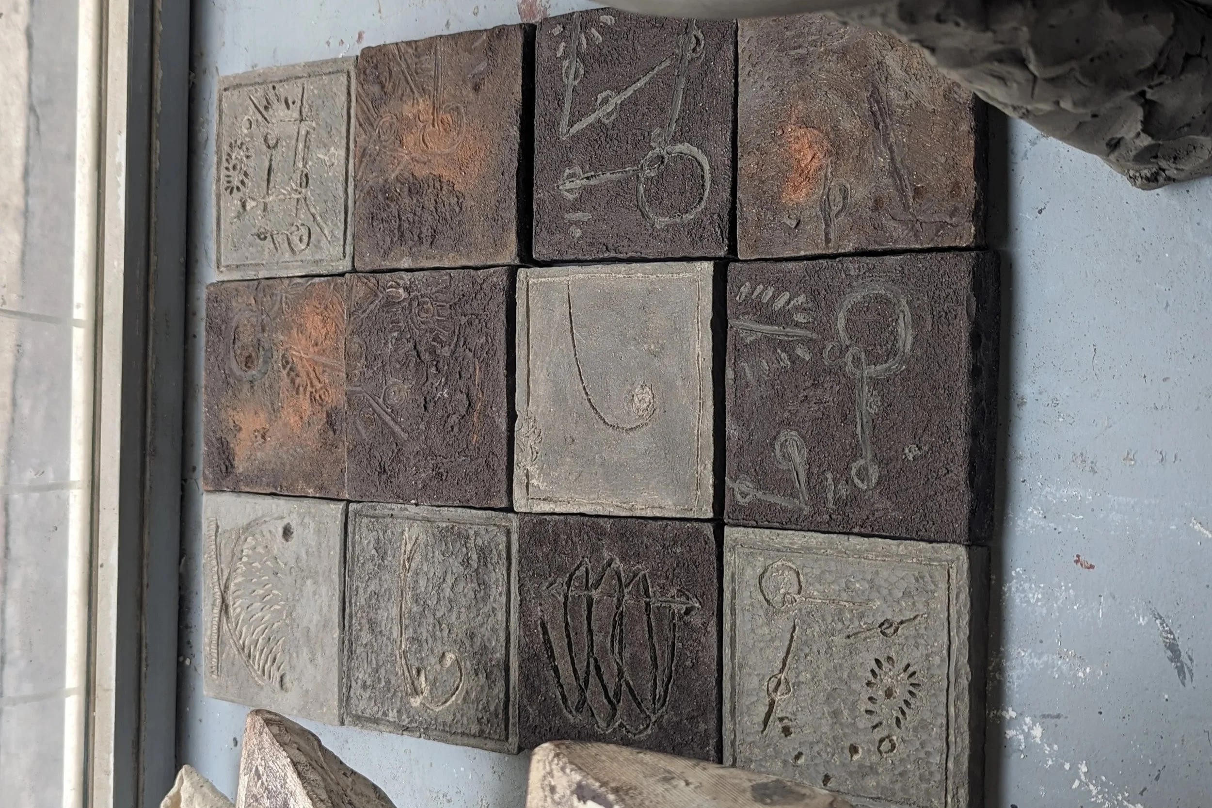 Carreaux de grès blanc gravés, enduit de barbotine. Dimensions : 10x10cm                                           