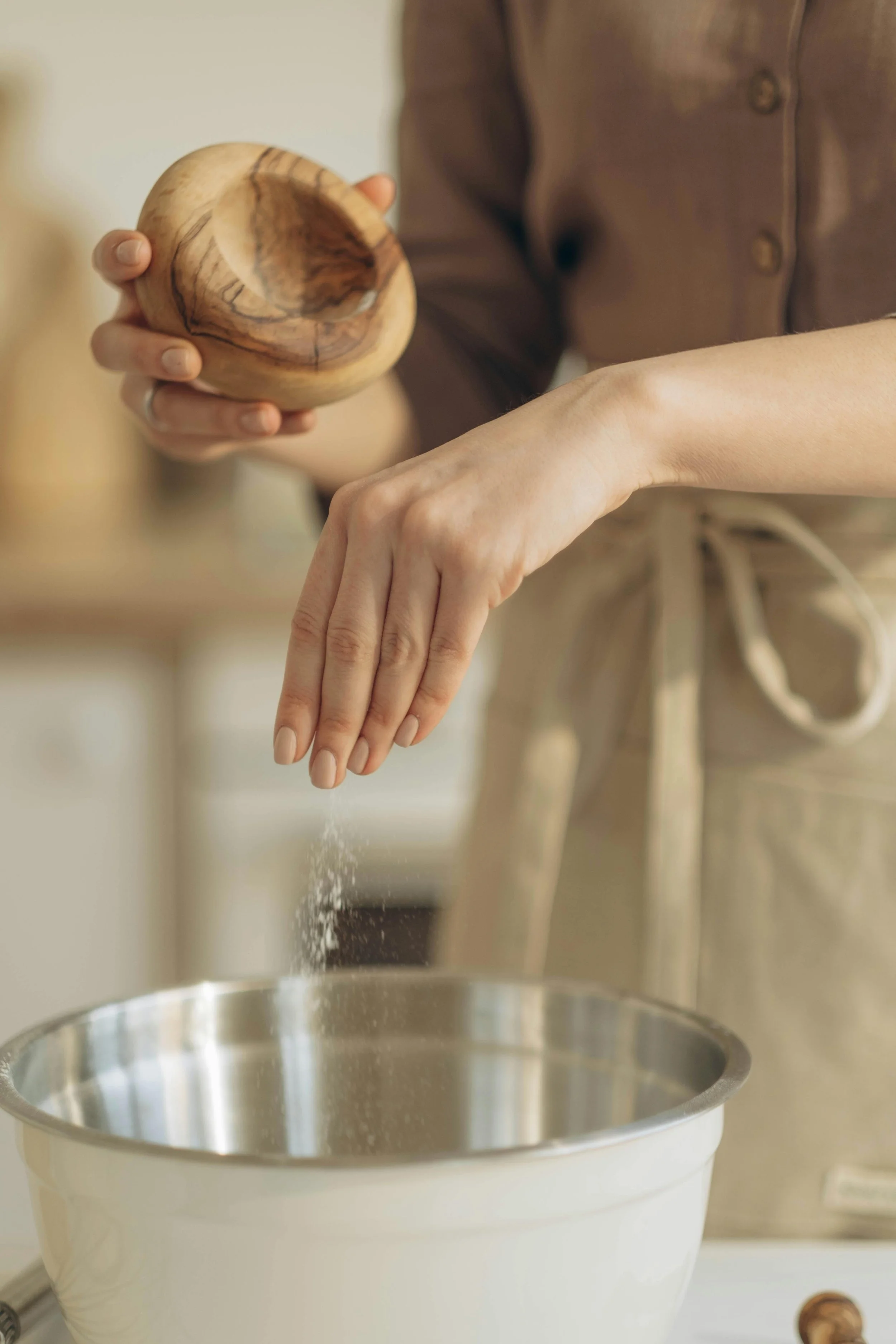 Hand sprinkling a pinch of salt into a mixing bowl, illustrating the Turkish recipe measurement “bir tutam” or “bir cimdik.”
