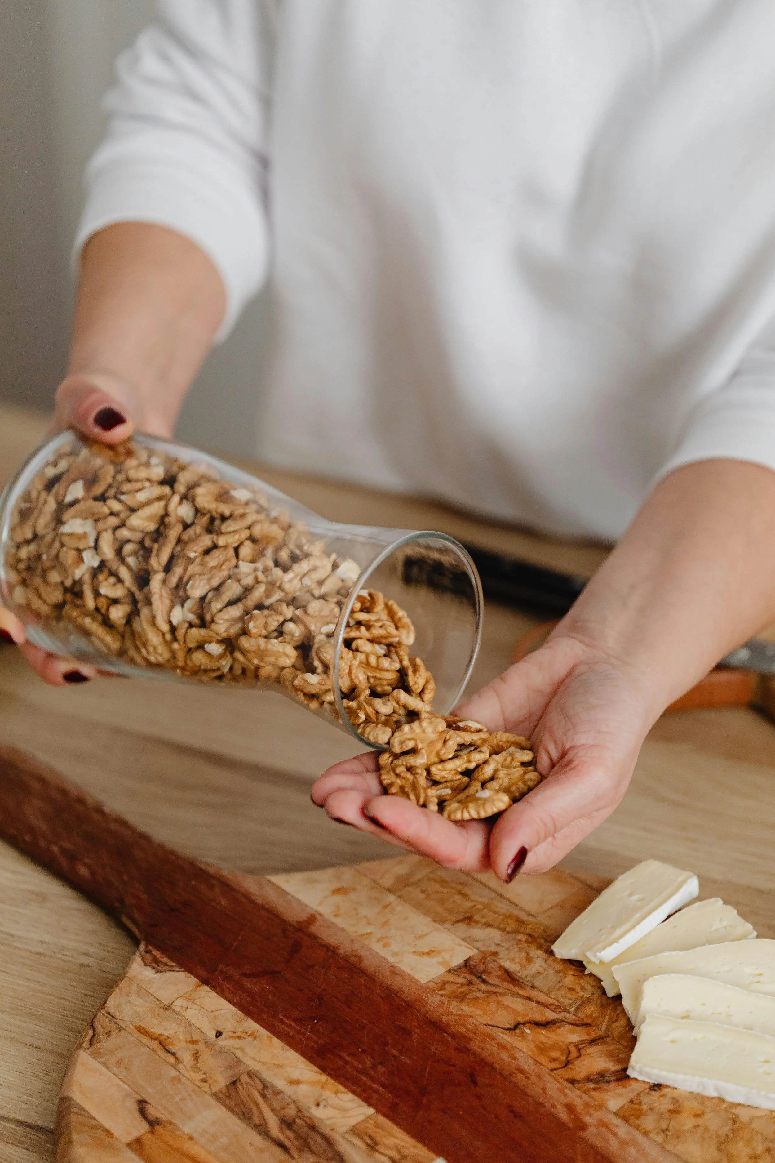 Walnuts being poured from a glass container into a hand, demonstrating the Turkish recipe measurement “bir avuç,” meaning a handful.