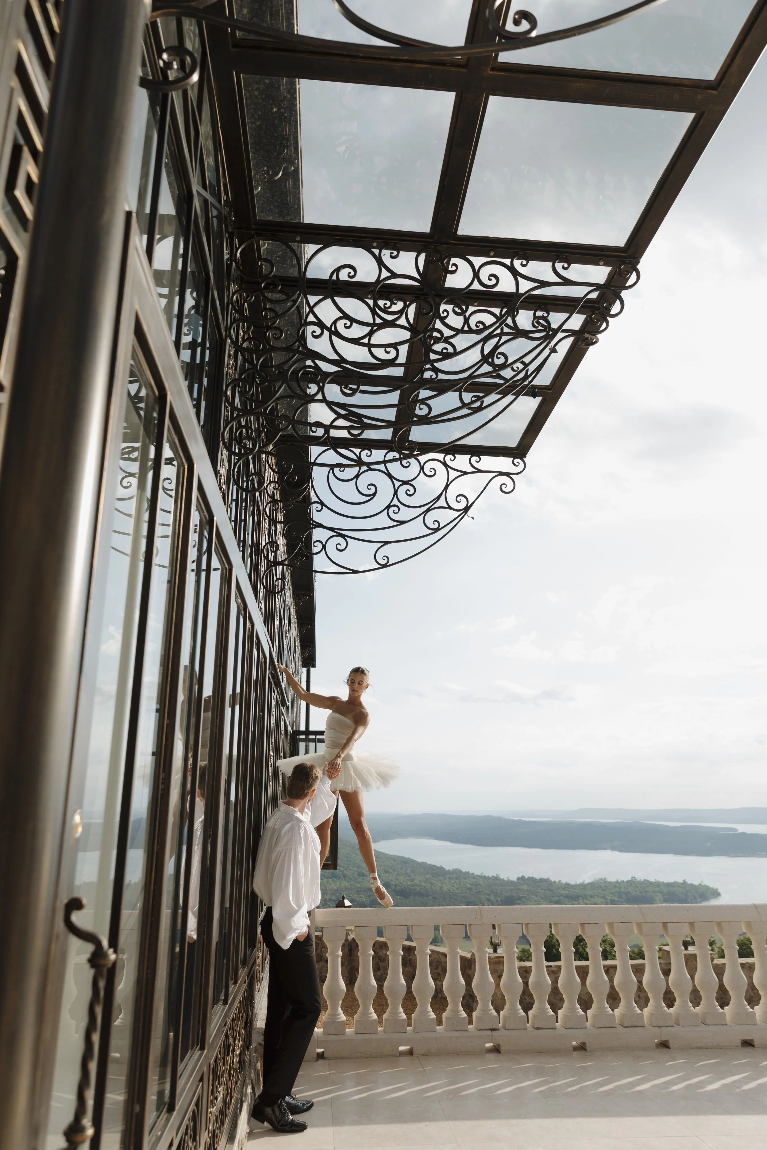 Bride on pointe in tulle ballet skirt with groom kneeling at her feet under ornate wrought iron canopy overlooking the lake at Stone Haven Weddings Alabama, editorial wedding photography by middle Tennessee wedding photographer Erin Daniel