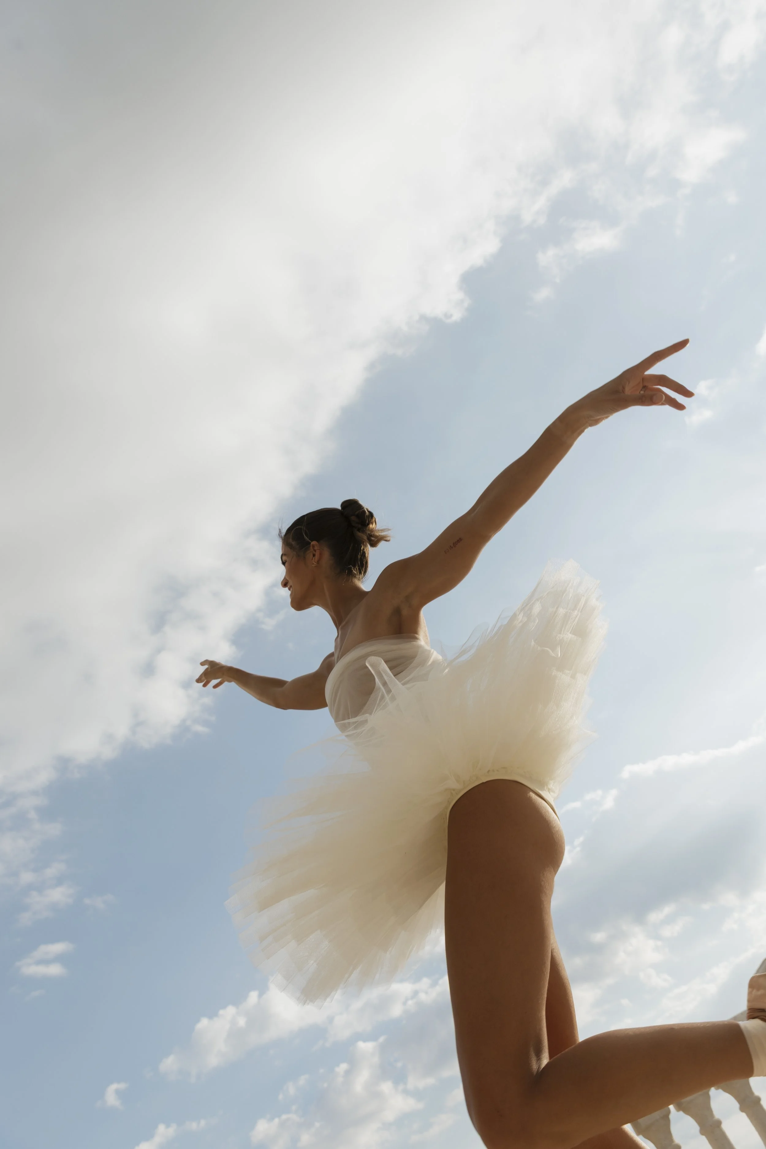 Bride mid-dance with arm extended toward the Alabama sky in flowing white tulle gown, ballerina-inspired bridal portrait at Stone Haven Weddings by middle Tennessee wedding photographer Erin Daniel