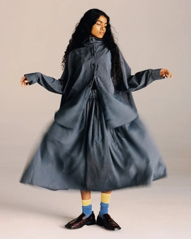 Oversized grey checked smock dress with a full gathered skirt, worn with yellow socks and brown loafers