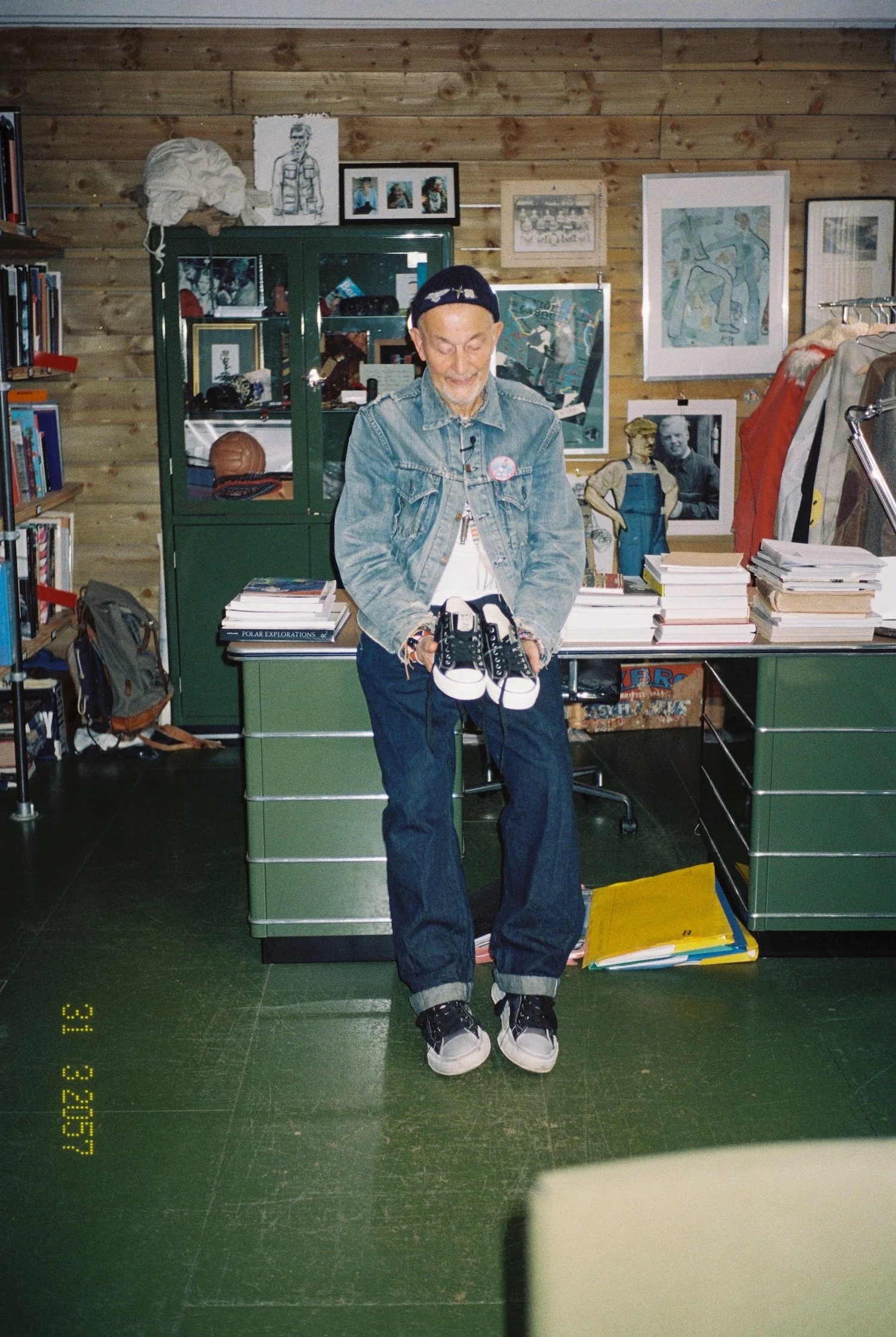 Nigel Cabourn in his office, holding one of his sneaker collabs,