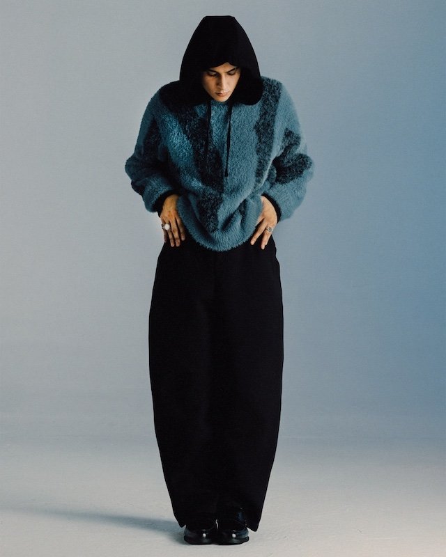 Teal brushed mohair hooded jacket over a black hoodie and wide black trousers, shot full length