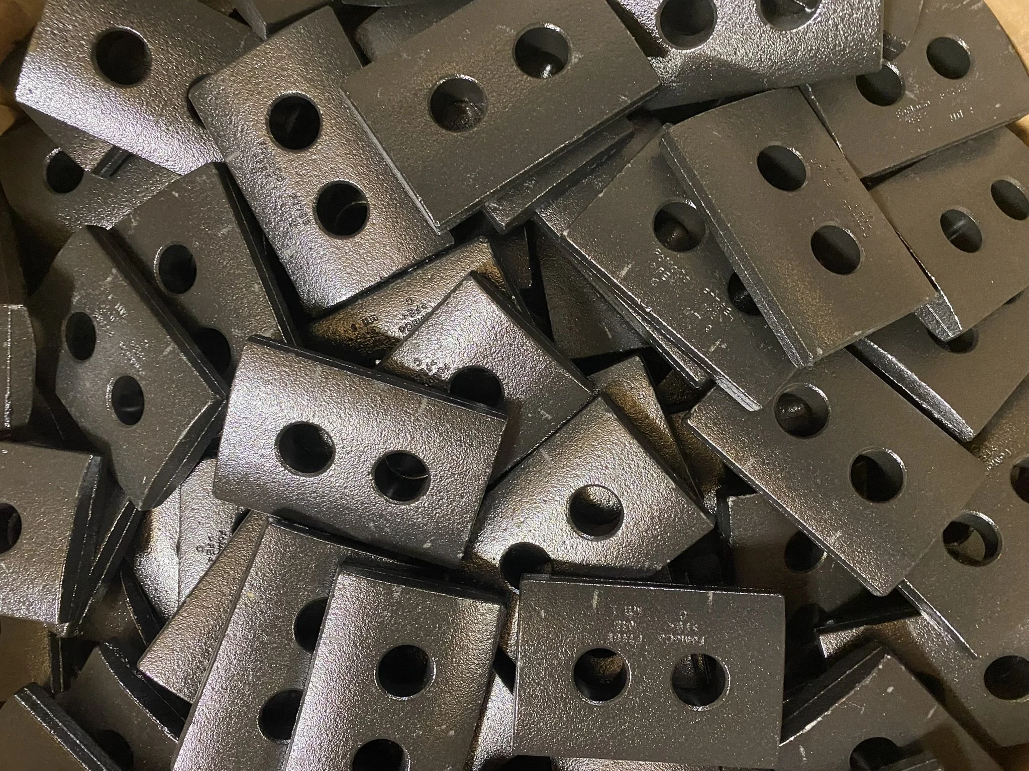 Stack of machined and robotically assembled metal brackets with drilled mounting holes, produced on Trinity Components Group's high volume machining cells