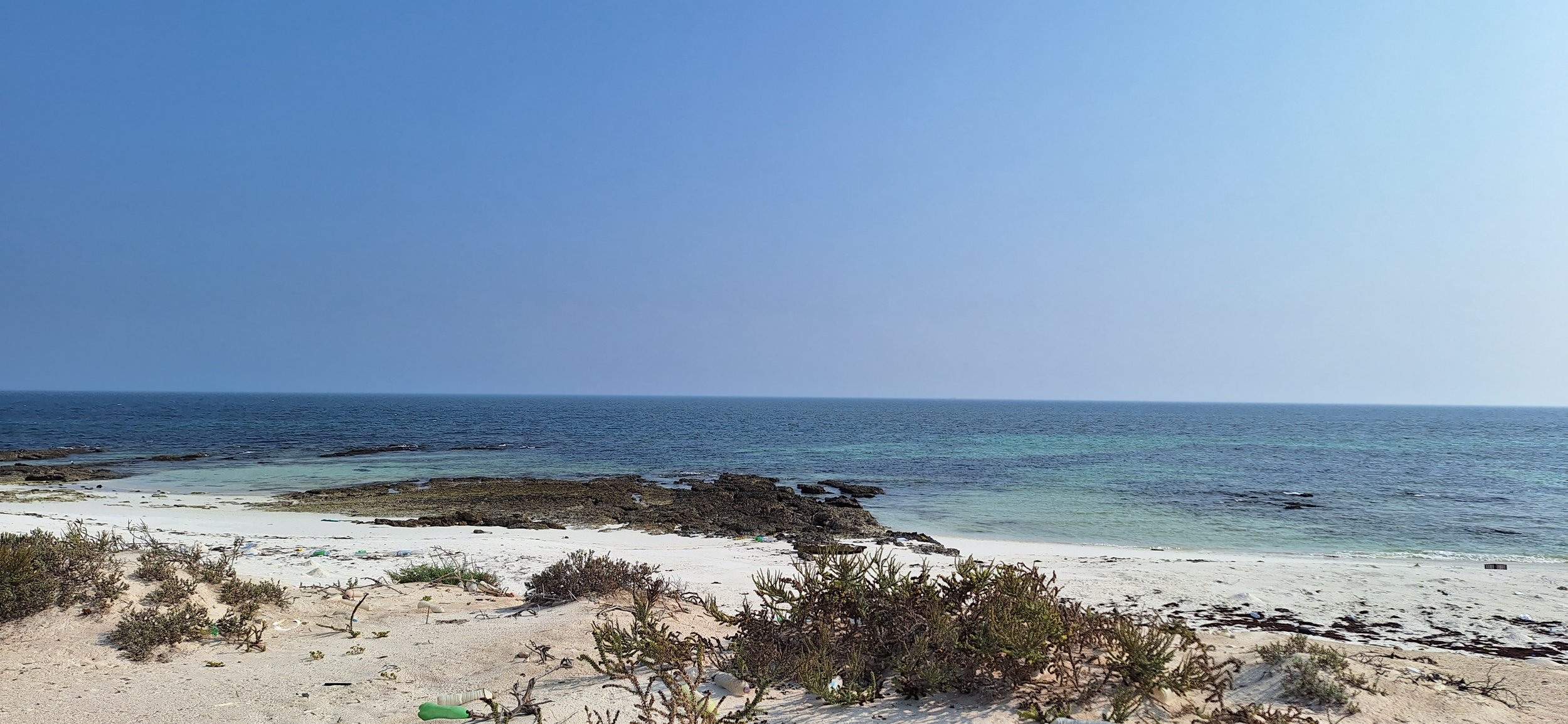 Empty white sandy beach with clear turquoise water and a bright blue sky
