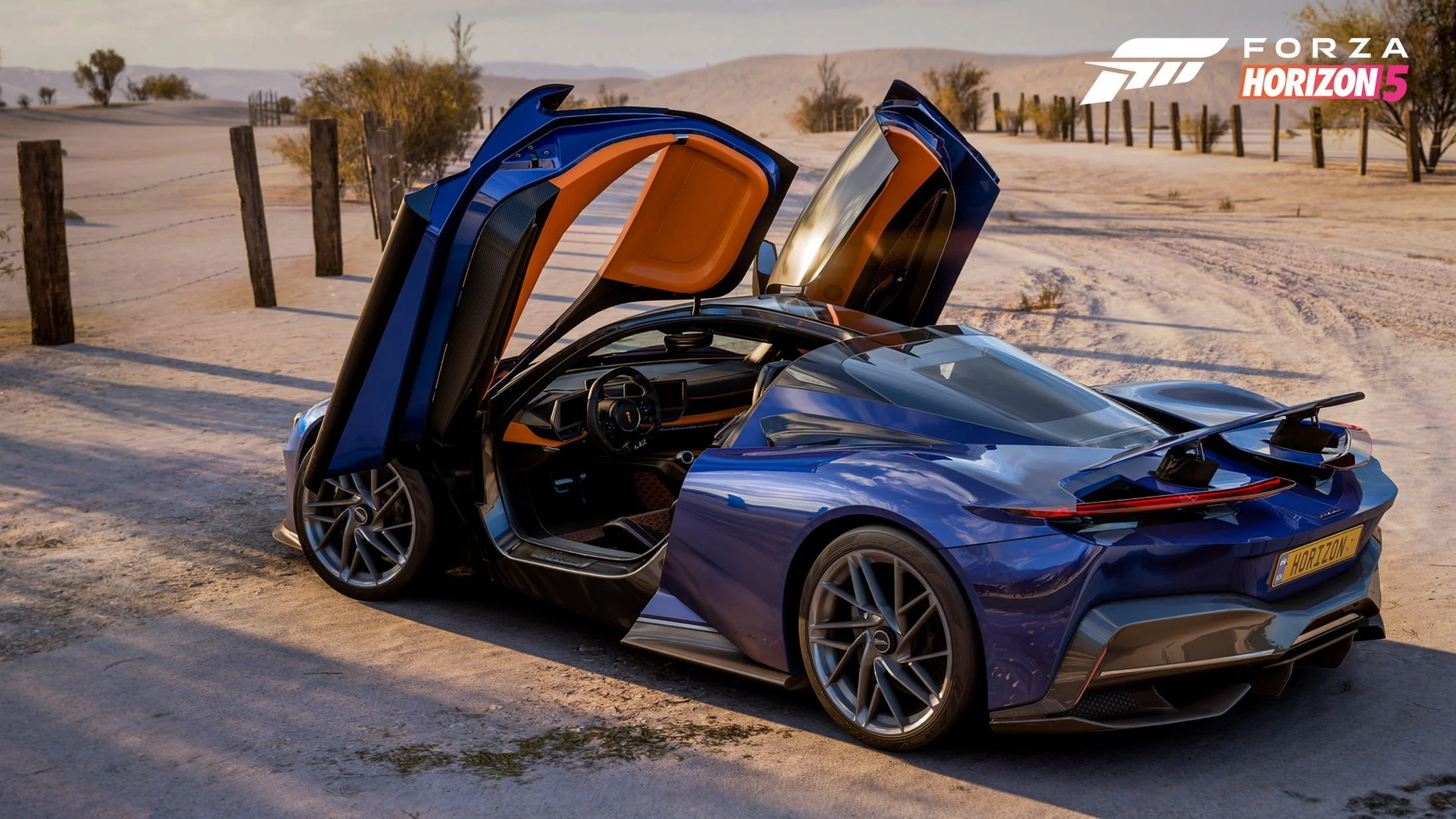 A blue sports car with gullwing doors open parked on a sandy dirt road in a desert landscape with a fence and distant hills, promotional for Forza Horizon 5.