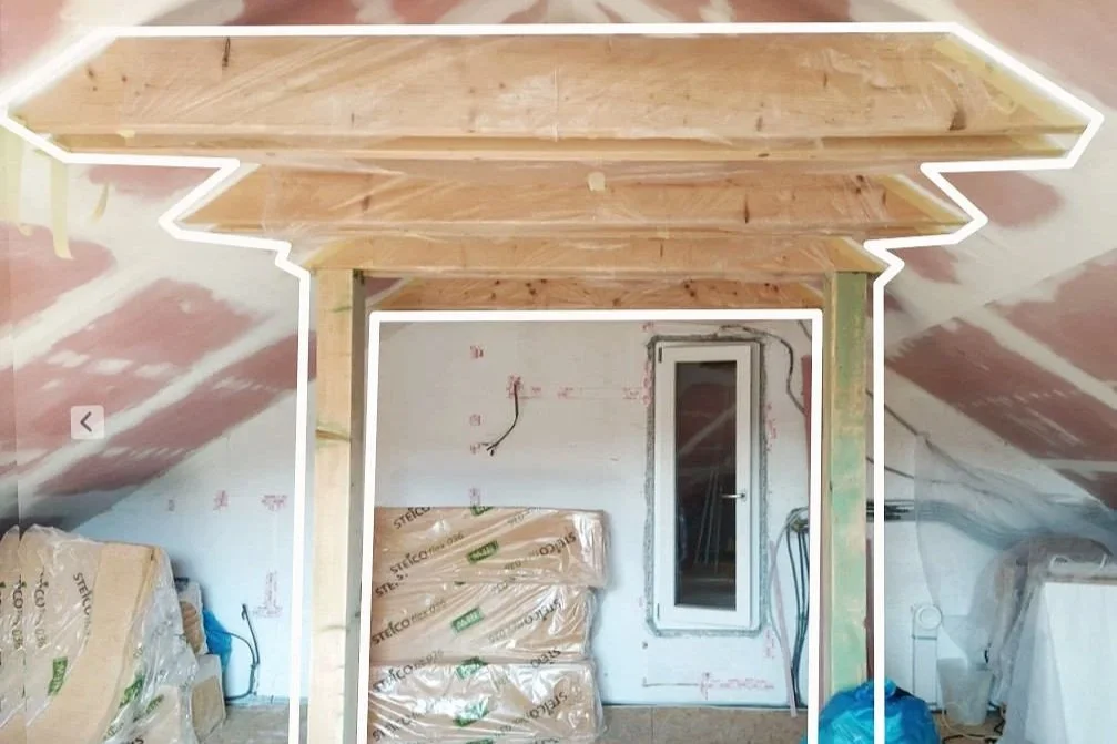 An attic room under reconstruction with dry walled sloped ceiling and wooden construction pillars
