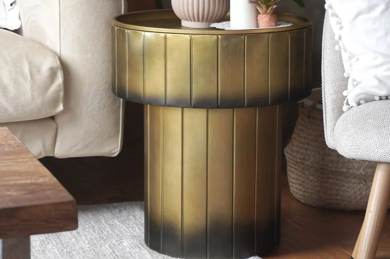 Round brass side table with hidden storage, styled with deco