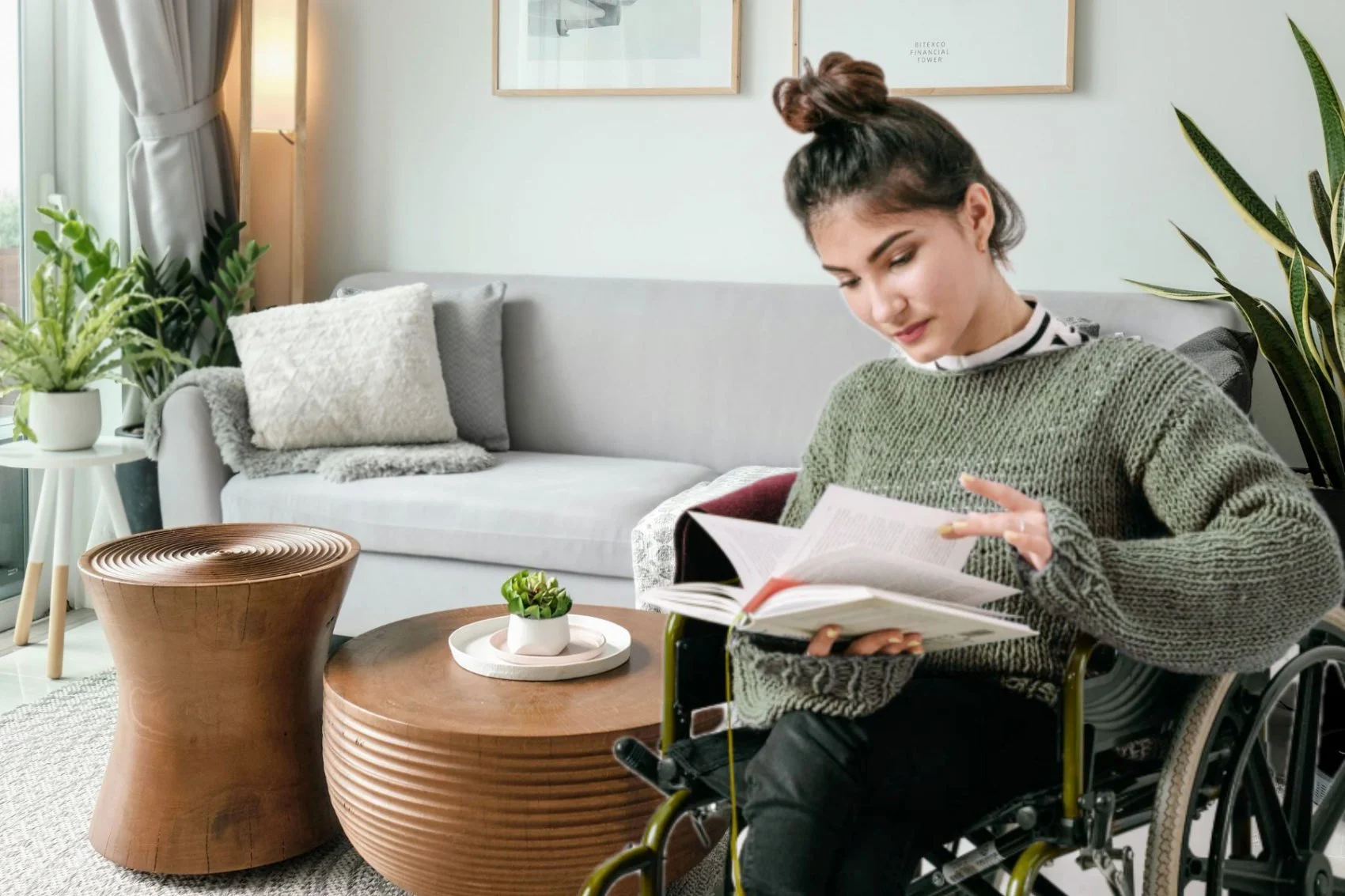 Bright, minimalist living room with wide open floor space, natural light, and clear pathways designed for wheelchair accessibility, with a young woman in a wheel chair at the foreground.