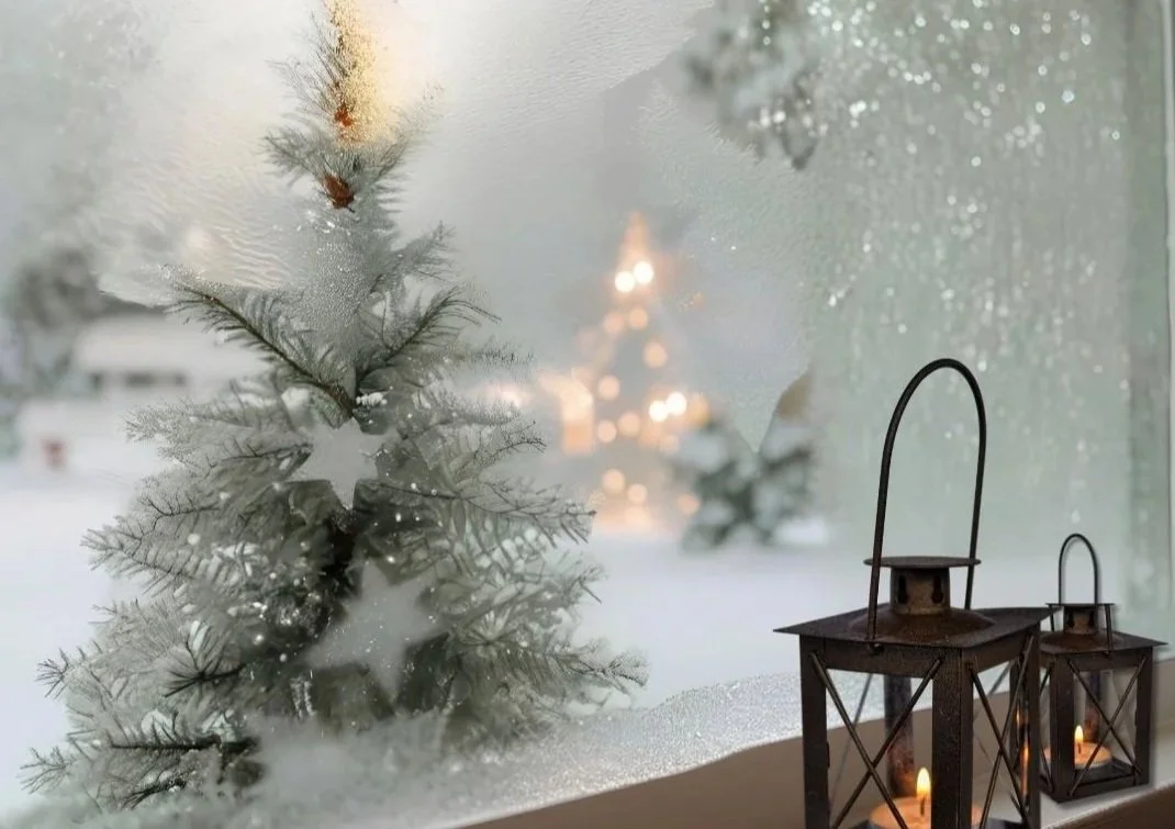 Twinkling fairy lights and lanterns illuminate a snowy garden, with warm candlelight glowing inside, creating a cozy holiday ambiance.