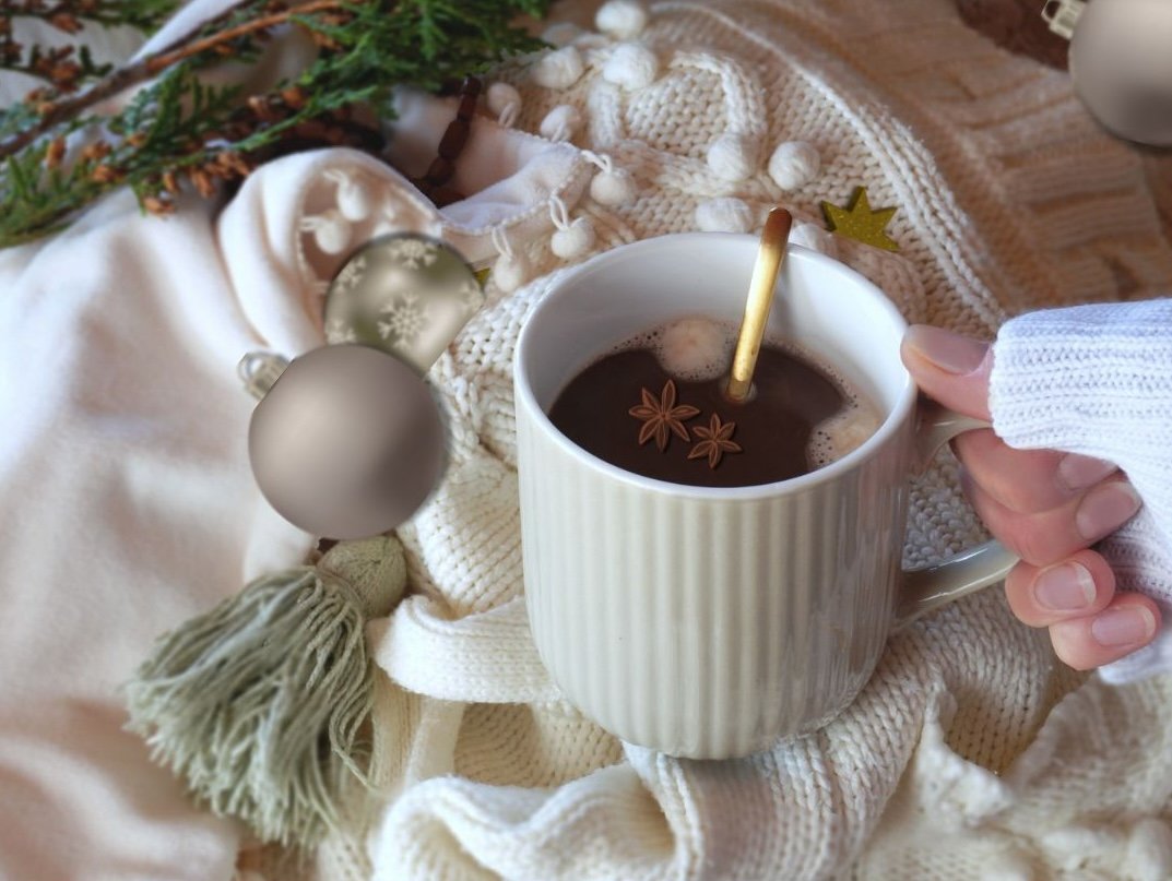 Mug of hot cocoa topped with marshmallows and warming spices, held over a cozy blanket, evoking comforting winter holiday moments