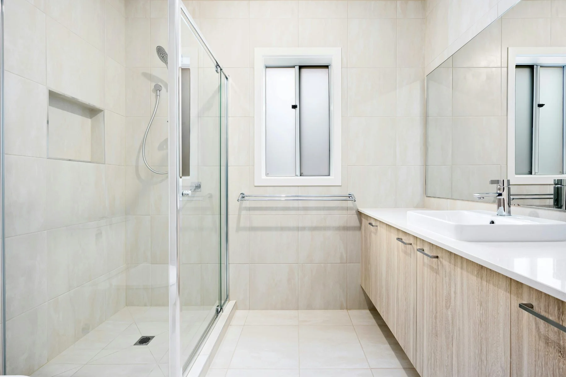 Wide wheel-chair accessible bathroom with a curb-less shower and bright interior.