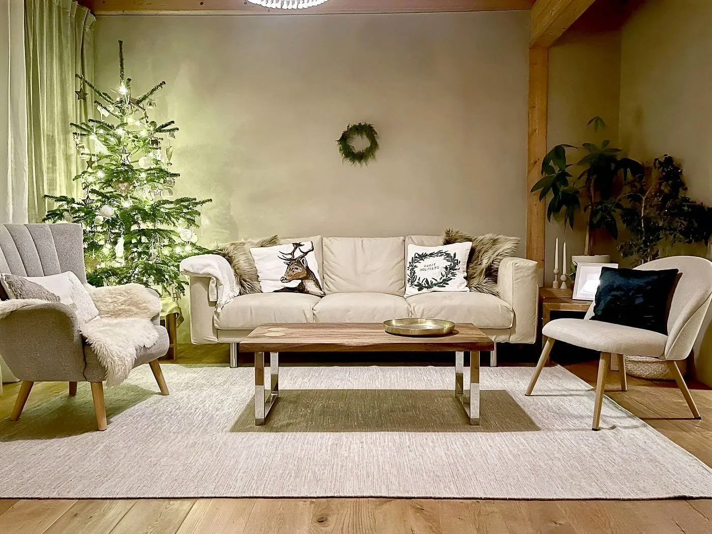Upgraded sustainable living room with beige sofa, cotton–wool rug, solid wood coffee table, two neutral chairs, and Christmas tree