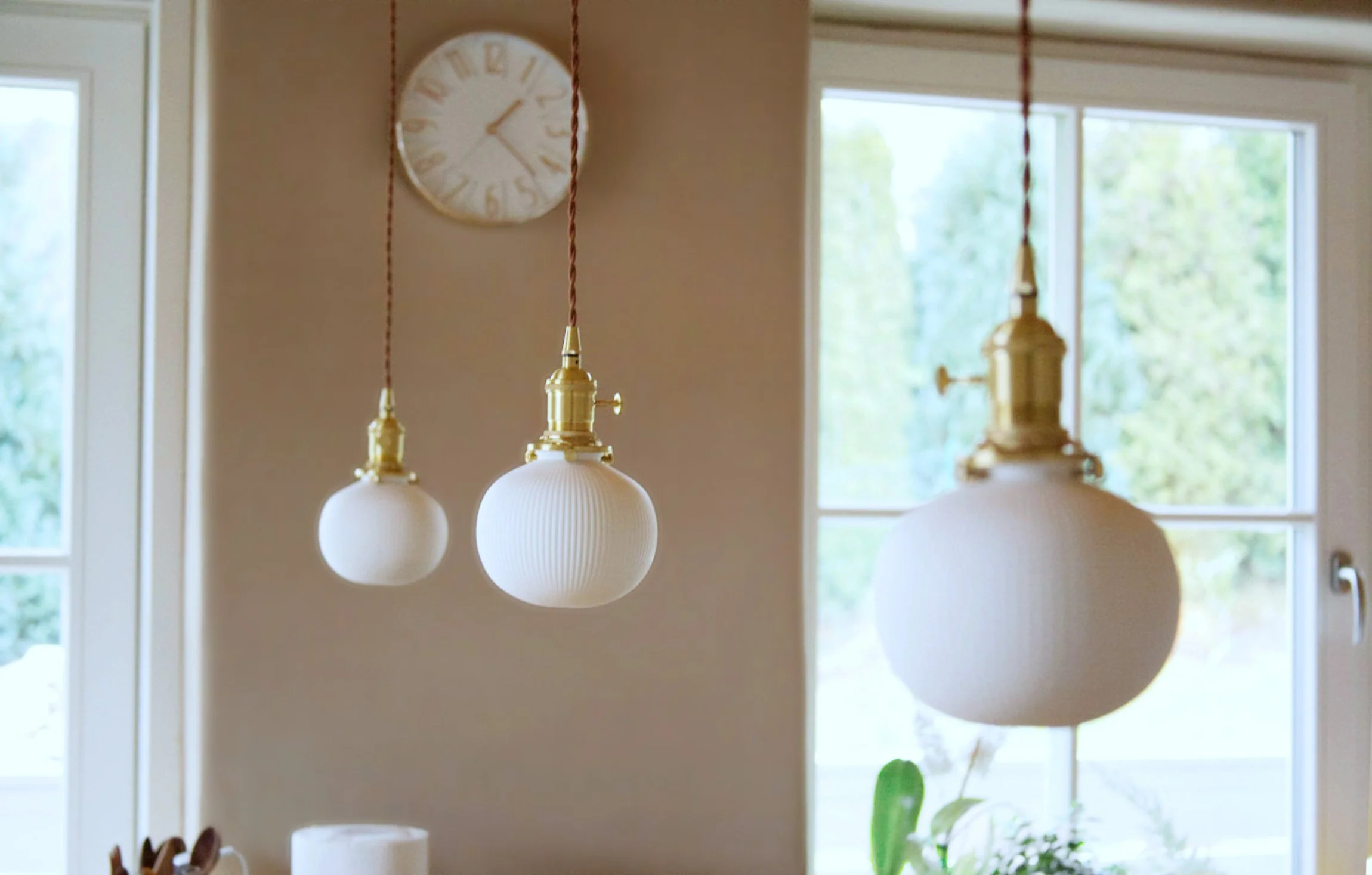 Three ceramic pendant lights above a kitchen island demonstrating warm home lighting design