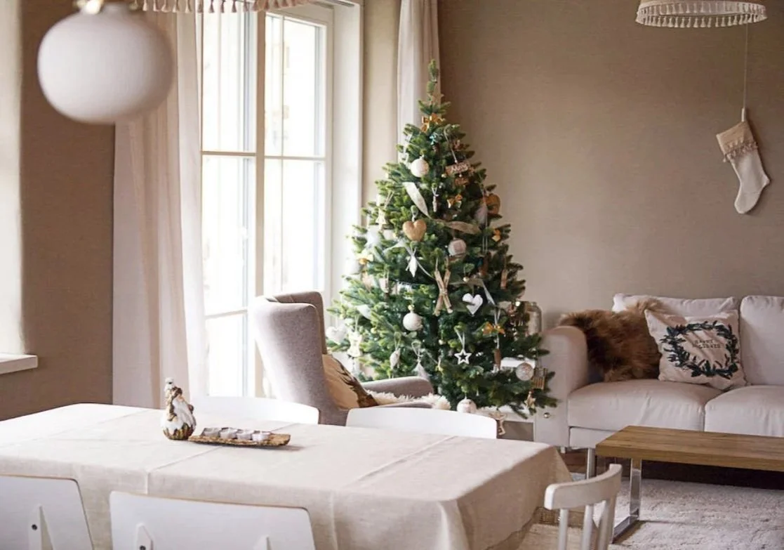 Christmas tree decorated in soft white, natural greenery, and minimalist ornaments in a cozy living room with neutral tones