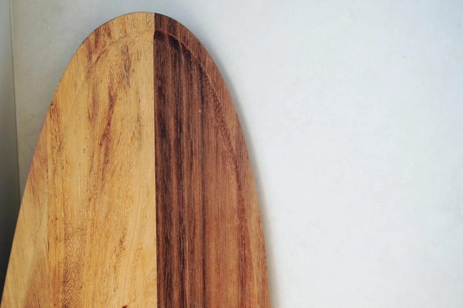Close-up of a wooden kitchen chopping board leaning against a counter, showing rich, restored wood grain.