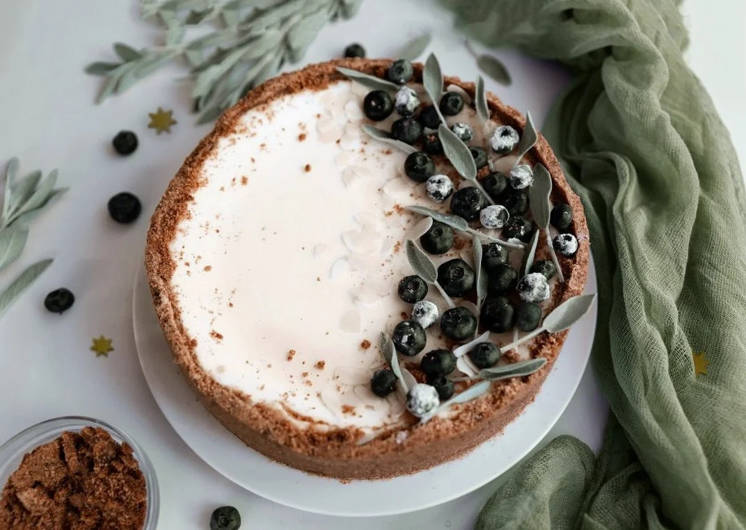 Festive Christmas cake decorated with fresh berries and sage, set on a rustic table, perfect for holiday gatherings
