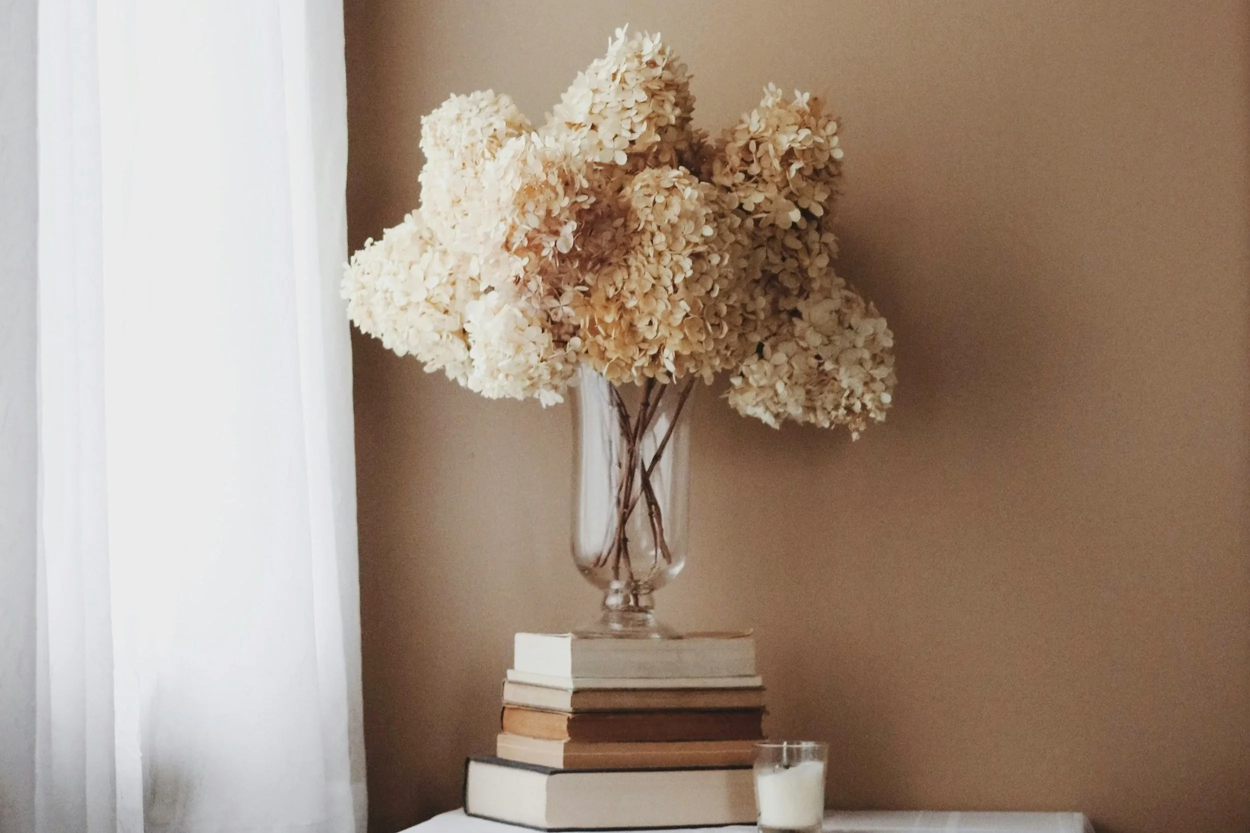 A calm corner with a vase placed on top of stacked books, creating a serene and minimal vibe.