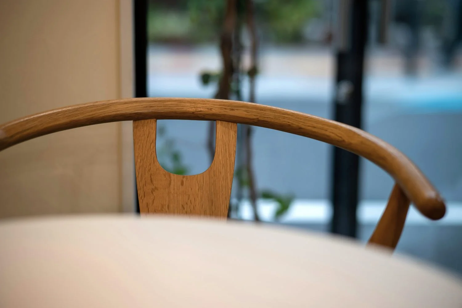 • A close-up detail shot of a wooden chair's curved back, showcasing how soft contours and soothing geometry lower stress in residential neuroarchitecture.