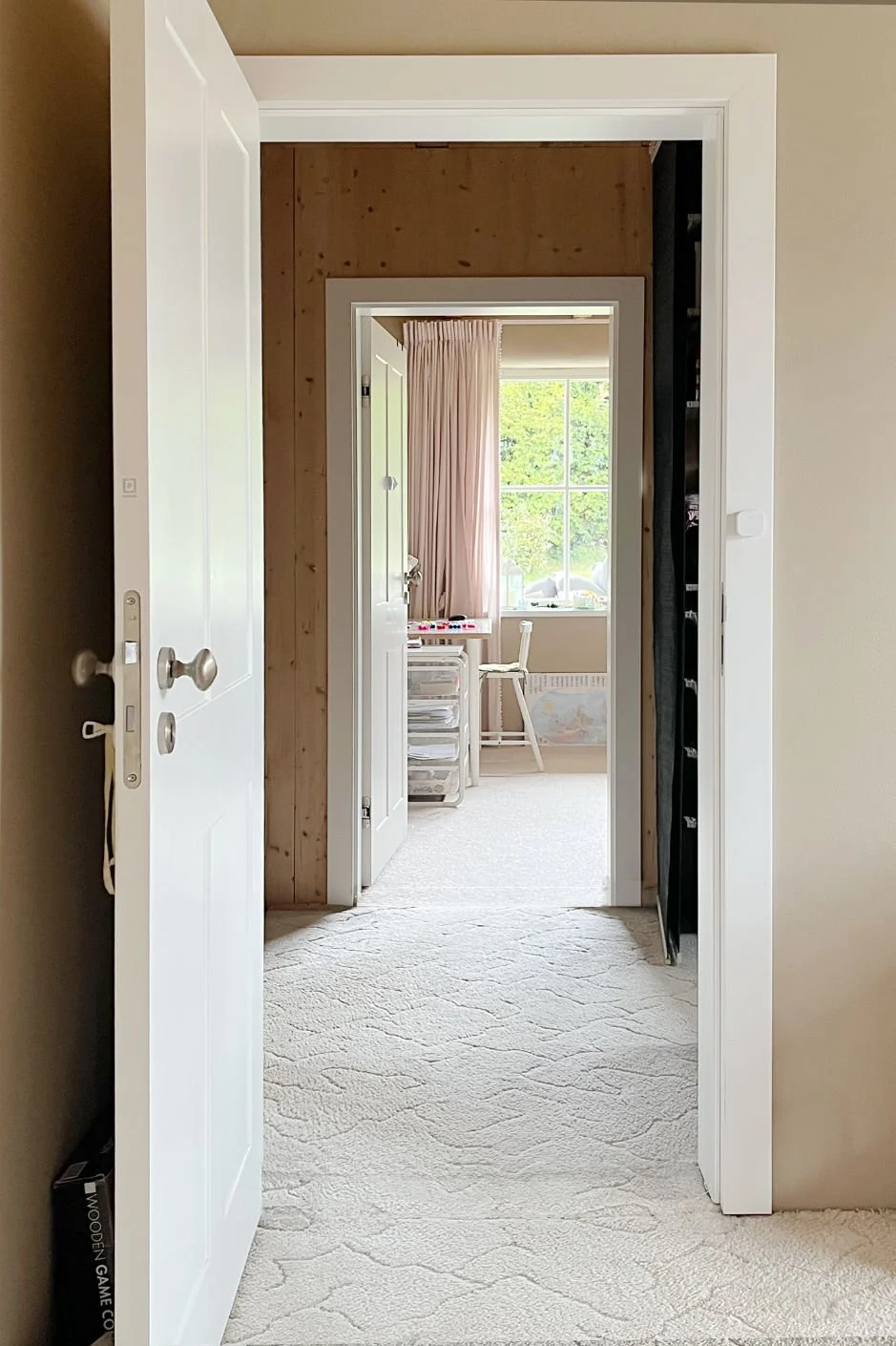 Bedroom with aligned interior doors and a bright window, creating a visual axis towards outdoor space beyond the room
