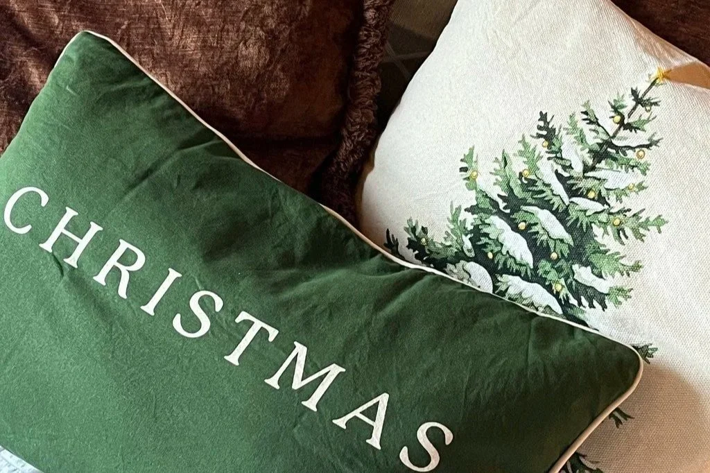 Collection of brown, green, and beige cushions in Christmas theme, arranged together, showcasing natural, cosy festive styling.
