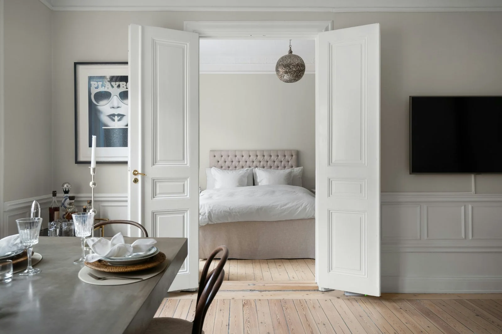 Wide open white double doors between dining room and bedroom in a modern interior, creating an inviting transitional view