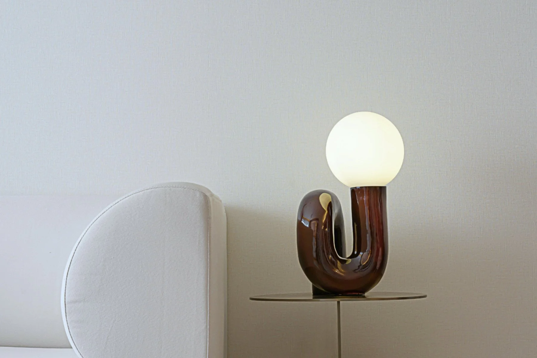 Small table lamp made from twisted glass, adding sculptural interest and artistic flair to simple white interior..