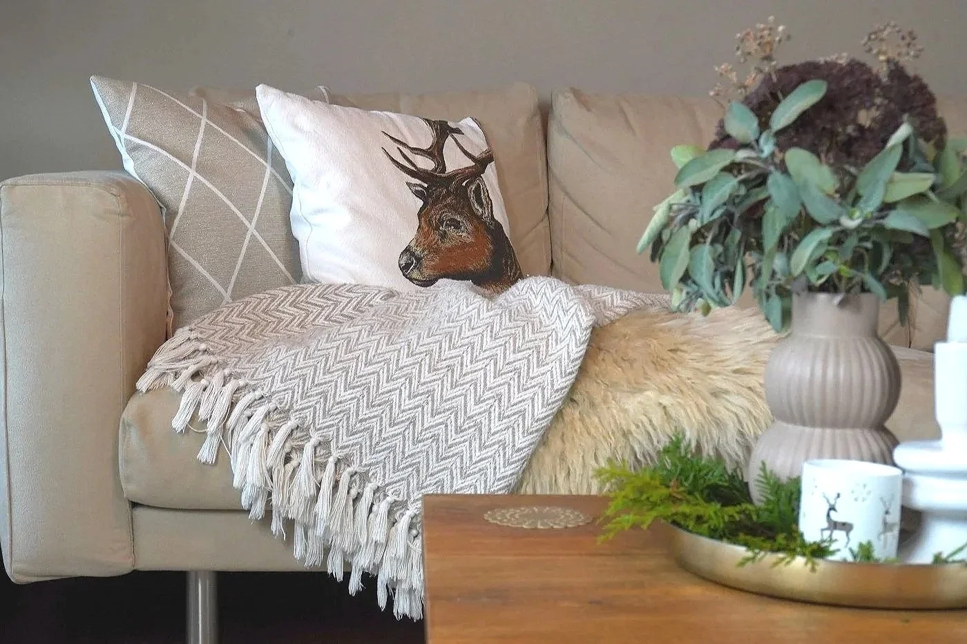 Cosy living room corner with cushions, throw, sheepskin, vase, and seasonal decor
